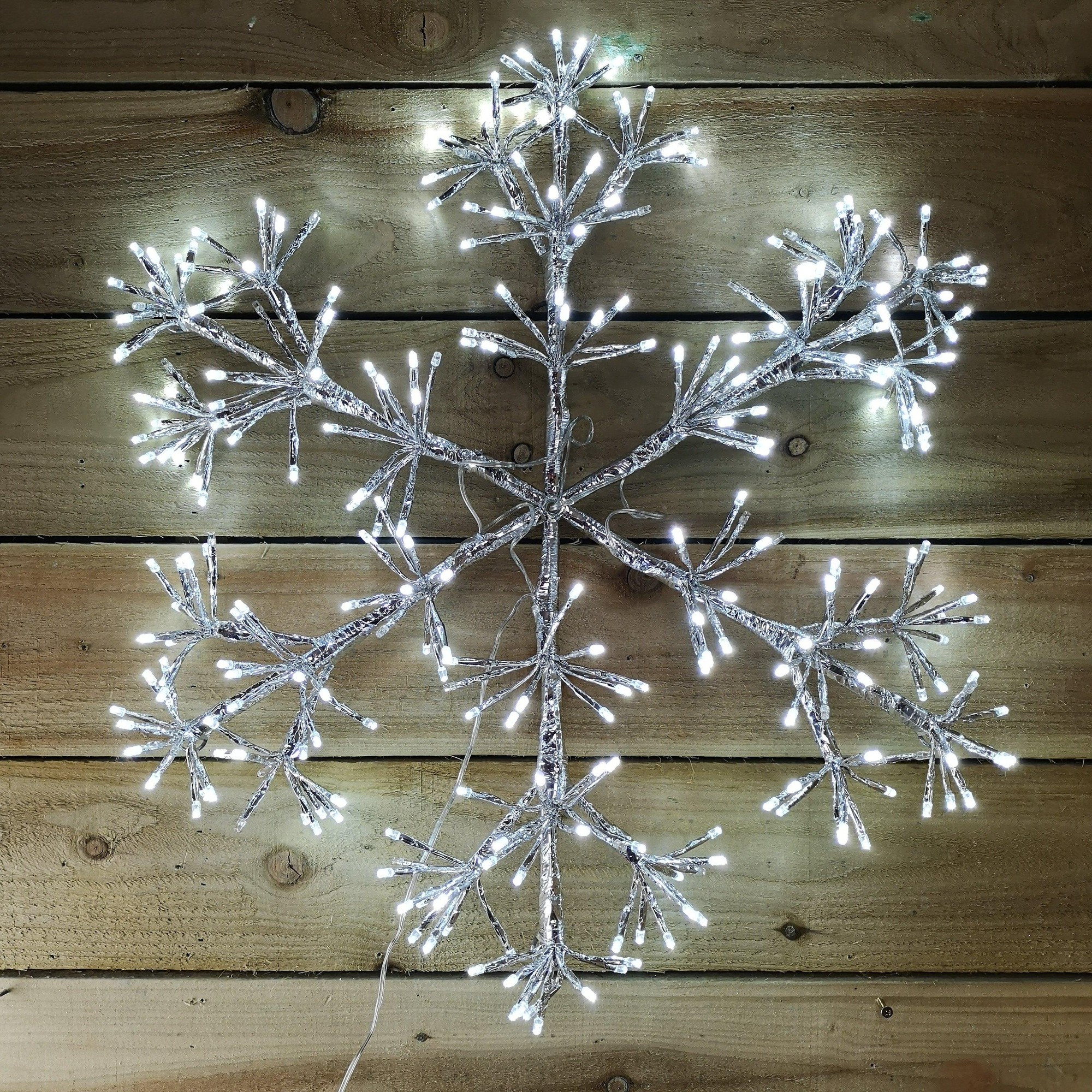 60cm silver starburst snowflake decoration featuring 300 white LEDs, crafted from a metallic material, with intricate branch-like extensions, ideal for wall or window display.