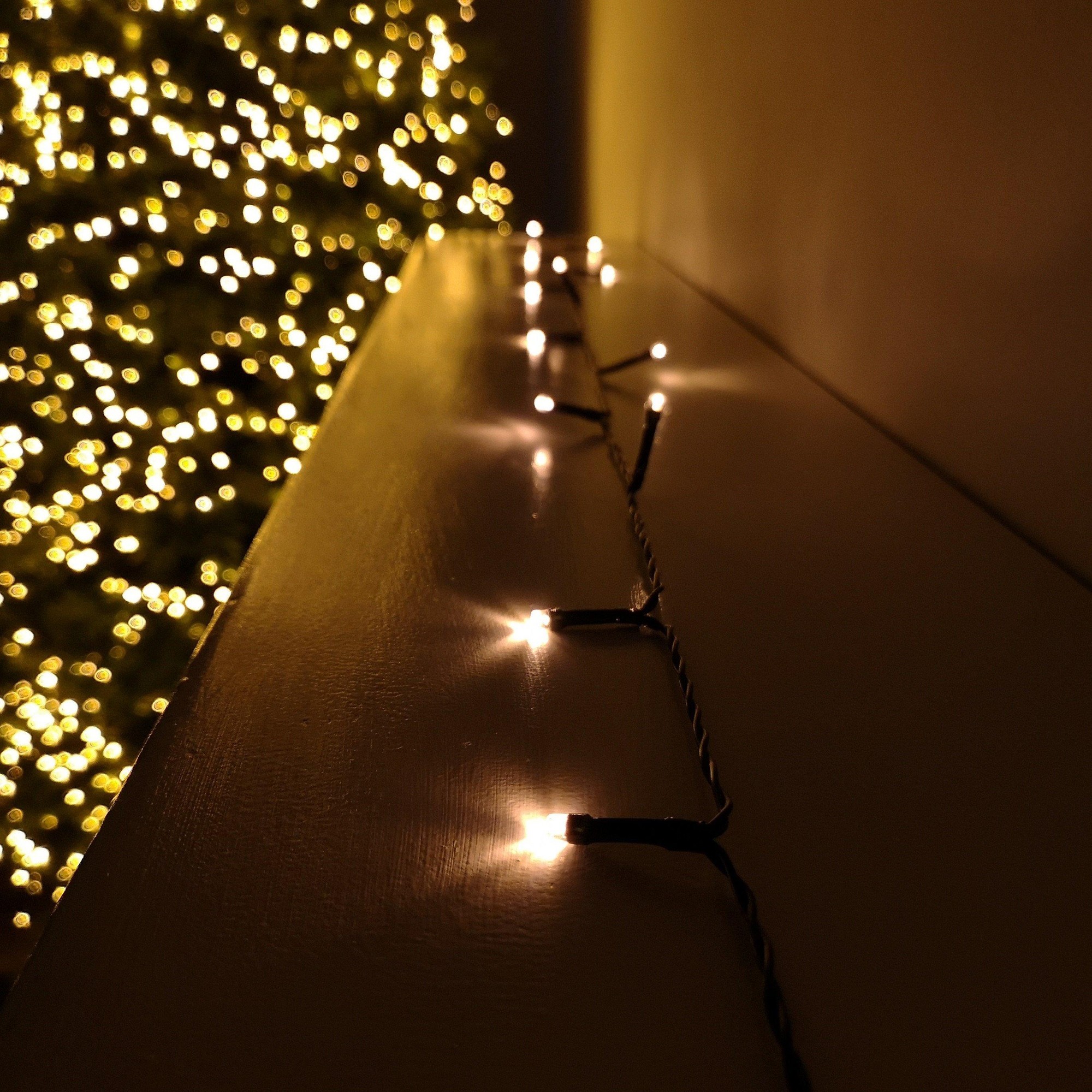 200 LED vintage gold string lights on a black wire, 20m long, with multi-function settings and timer, illuminating a warm glow against a blurred background of a Christmas tree.