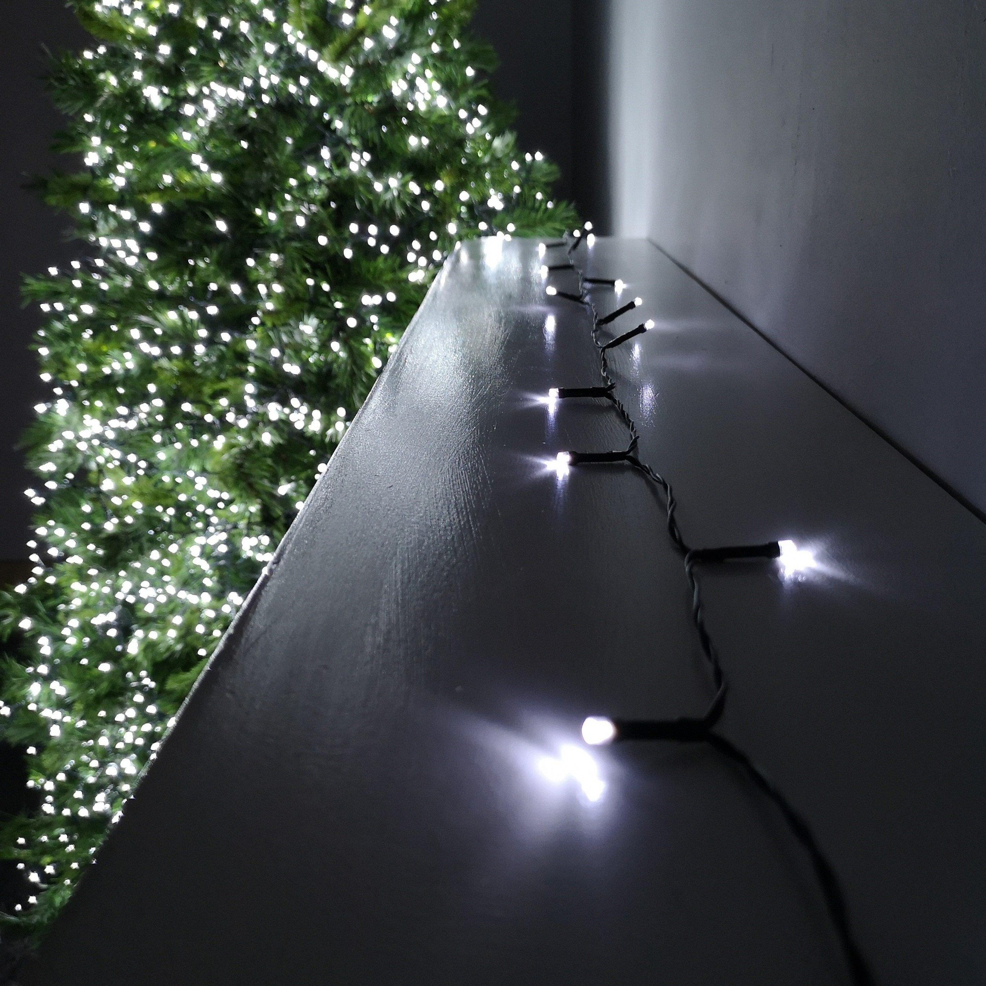 Battery-operated 5m string lights featuring 50 cool white LEDs on a dark wire, designed for indoor or outdoor use, with a timer function, set against a backdrop of a lit Christmas tree.
