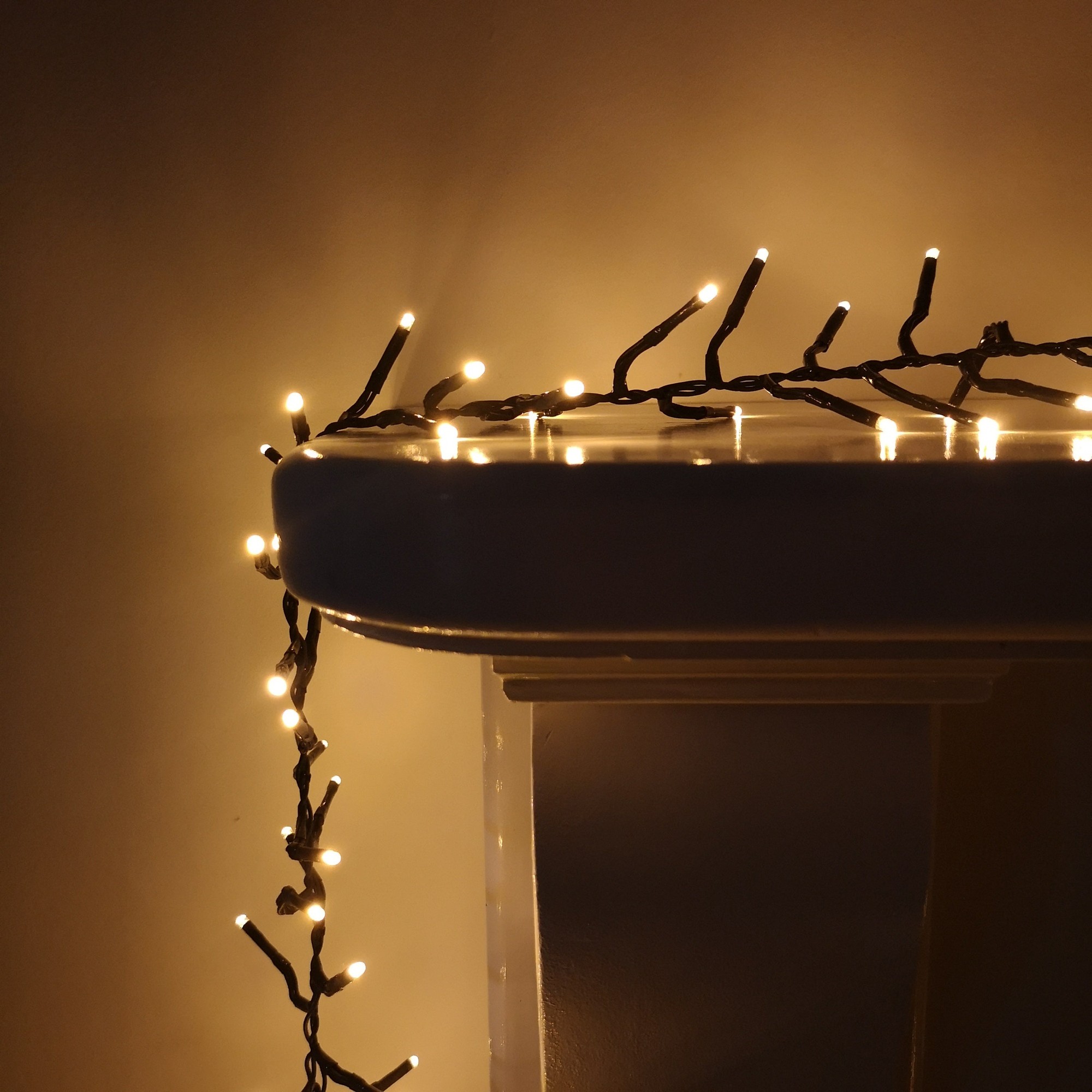 Vintage gold LED cluster lights with a dark brown wire, showcasing warm white bulbs, elegantly draped over a white surface, ideal for indoor or outdoor Christmas decor.