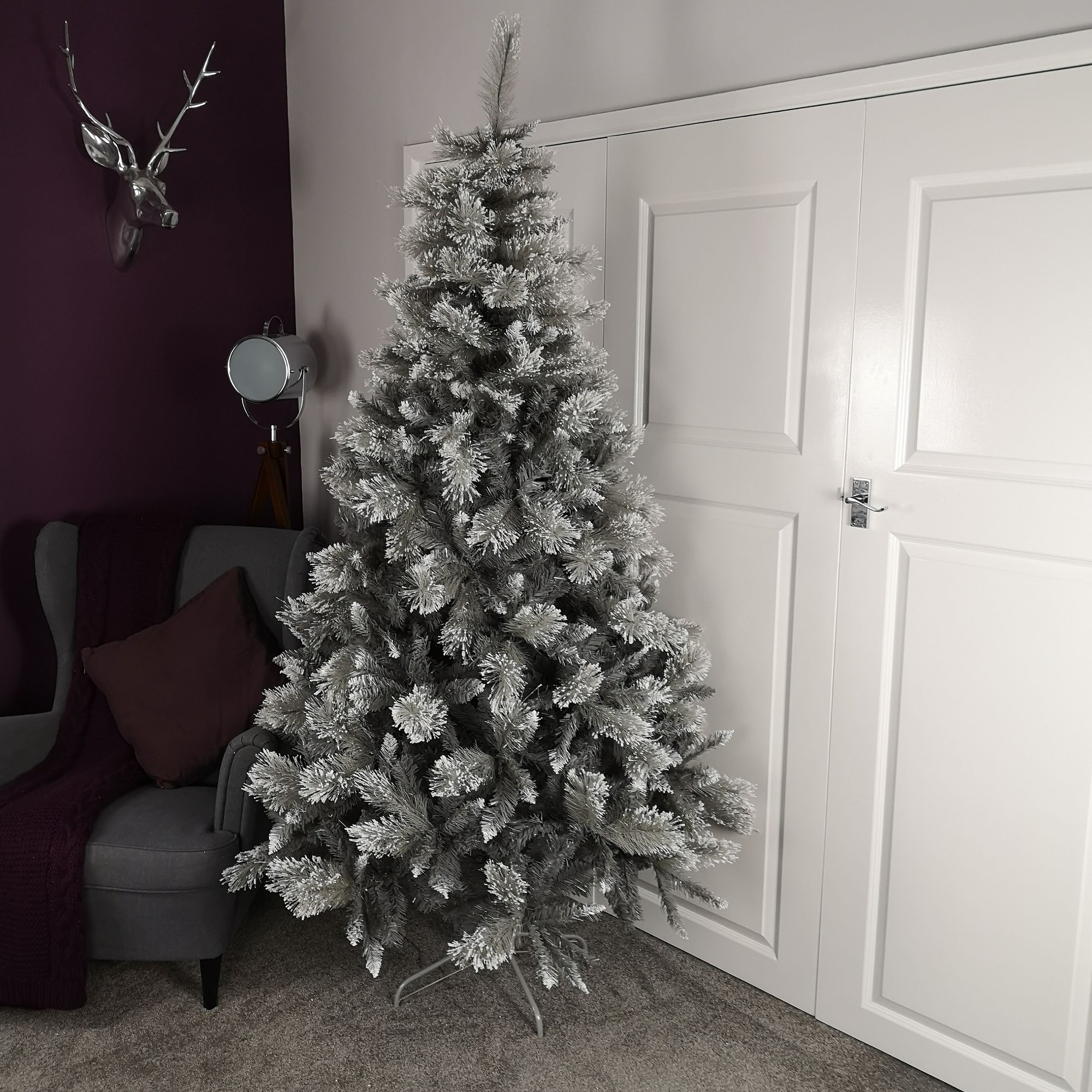7ft grey PVC Christmas tree featuring 861 cashmere tips, showcasing a full, frosted appearance, positioned in a cozy room next to a grey armchair and white closet doors.