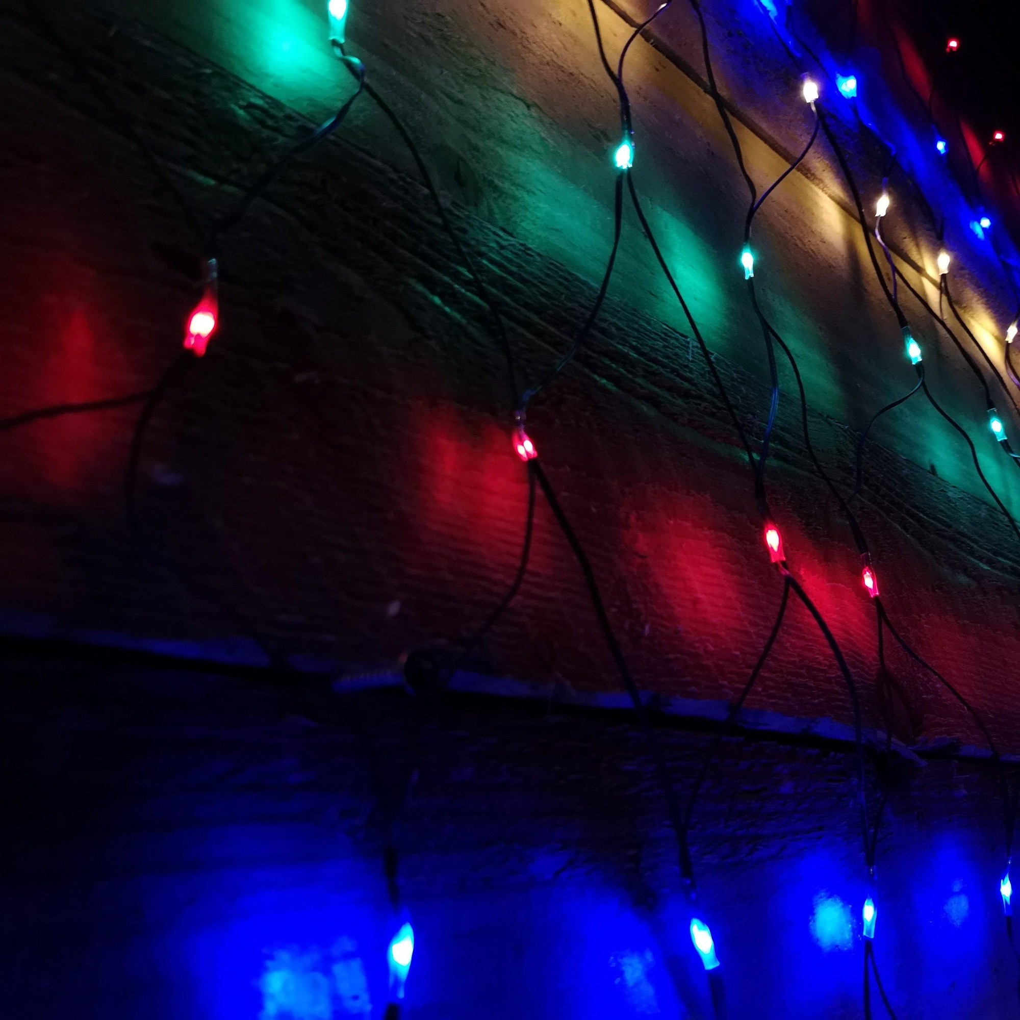 Multicoloured 180 LED Christmas net lights measuring 1.7m x 1.2m, featuring vibrant red, green, blue, and white bulbs on a dark wire, ideal for festive decorations.