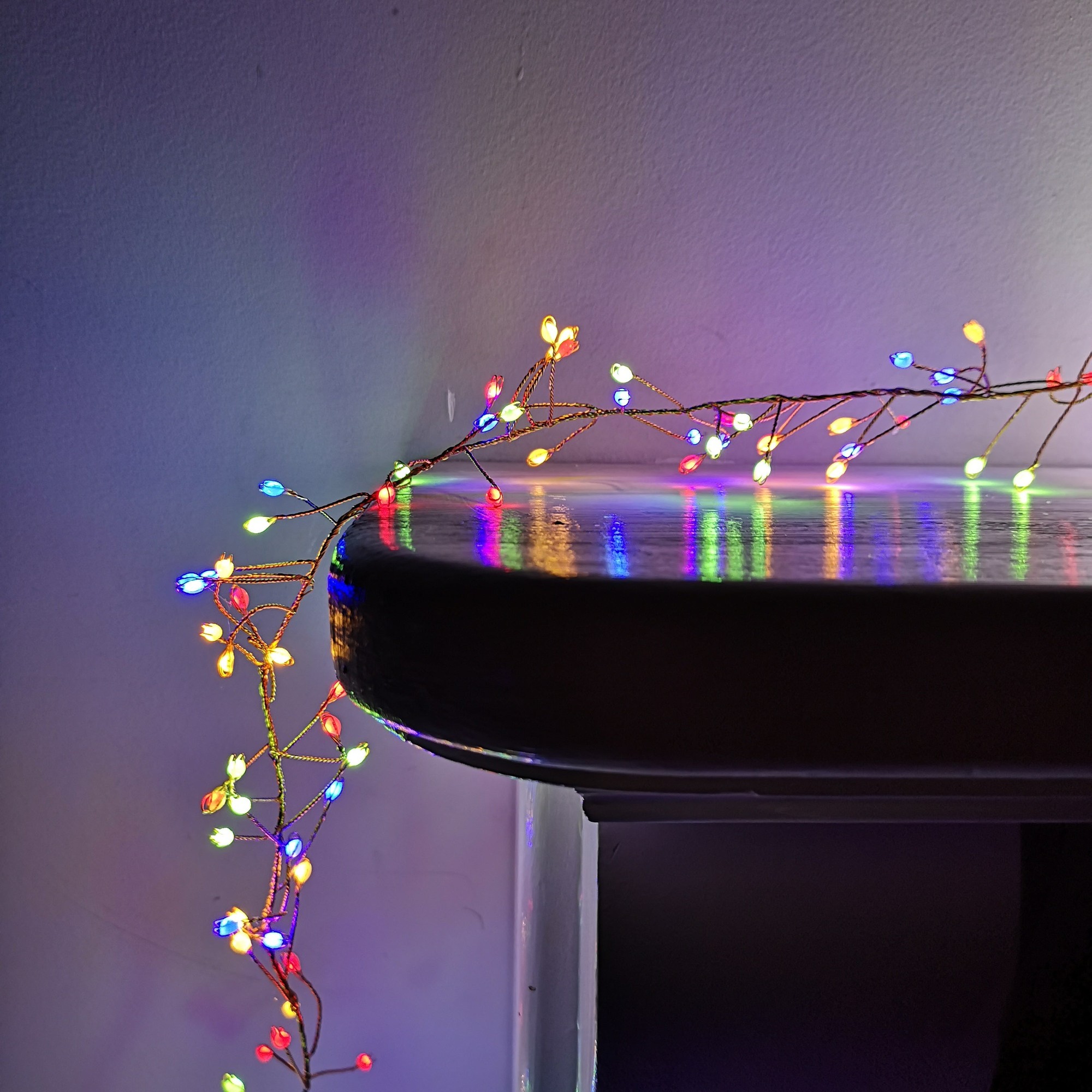 Multicoloured LED cluster lights with a flexible wire design, featuring 800 bulbs, draped over a ledge, ideal for indoor and outdoor festive decor, includes a timer function.