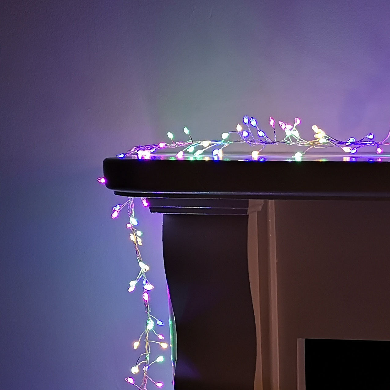Multicoloured 800 LED cluster lights on a wire, designed for indoor and outdoor use, featuring a timer function, draped over a dark surface.
