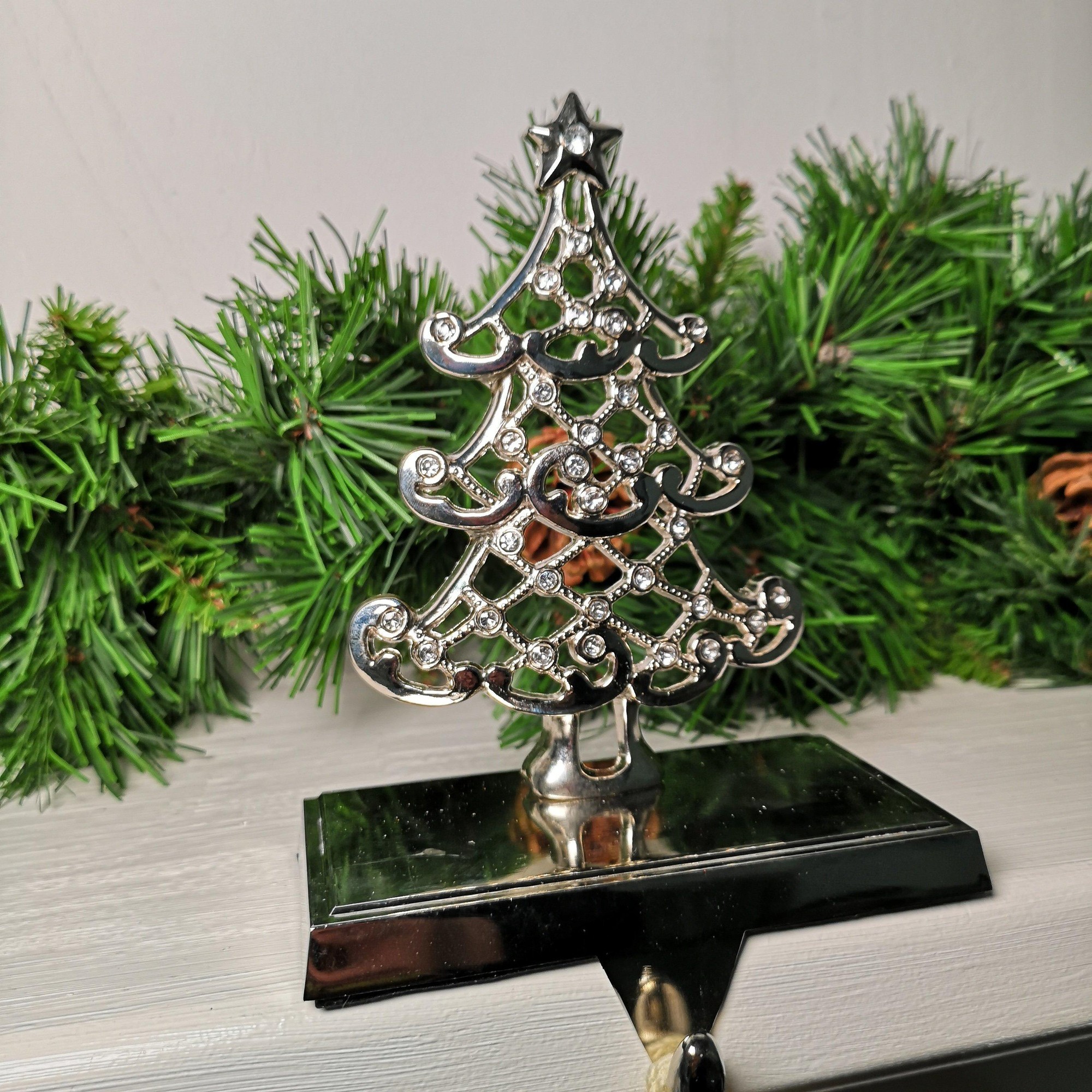 Premier 16cm silver Christmas stocking hanger shaped like a decorative tree, featuring intricate designs and a shiny finish, resting on a flat base with a hook.