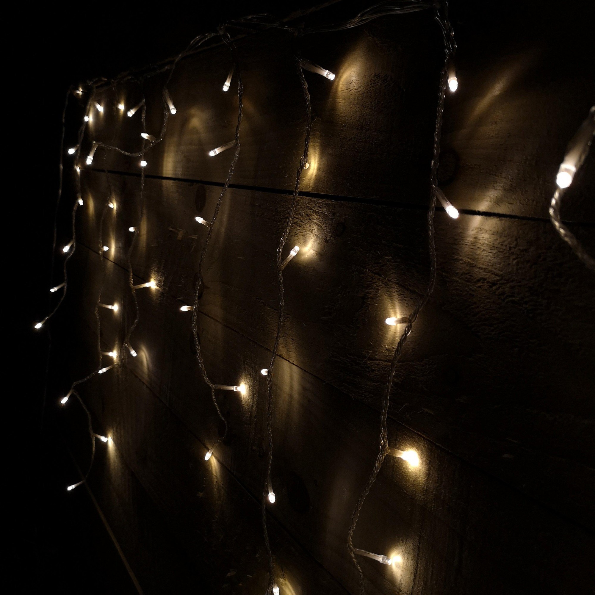 Warm white LED icicle lights with a clear cable, featuring 720 bulbs, designed for indoor and outdoor use, showcasing a snowing effect with a timer function.