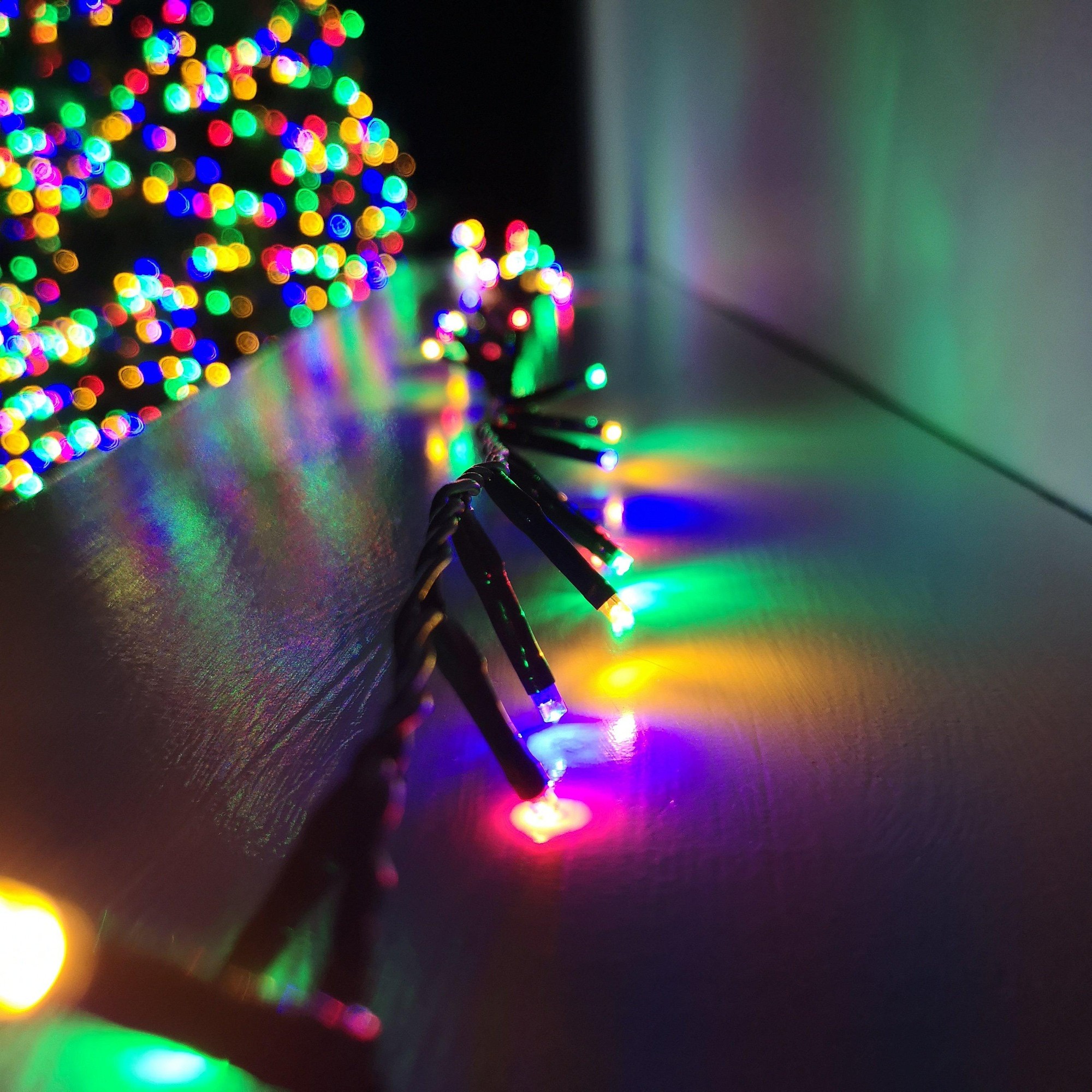 Multicoloured LED string lights with a black wire, showcasing vibrant red, green, blue, and yellow bulbs, designed for indoor and outdoor use, featuring a timer function.