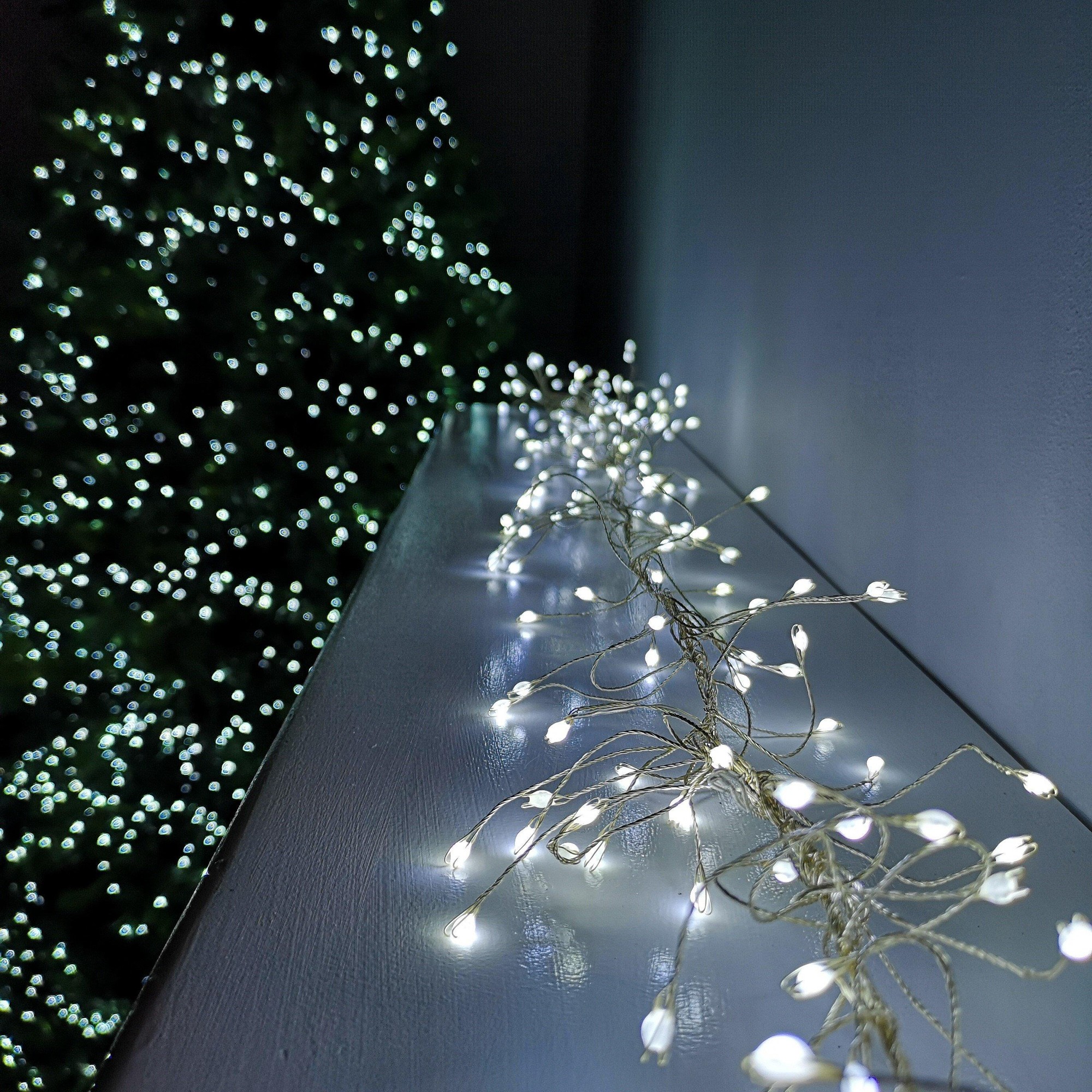 Cool white LED garland wire lights with 8 functions, measuring 1.8m, featuring a flexible design and twinkling effect, set against a softly lit background of a Christmas tree.