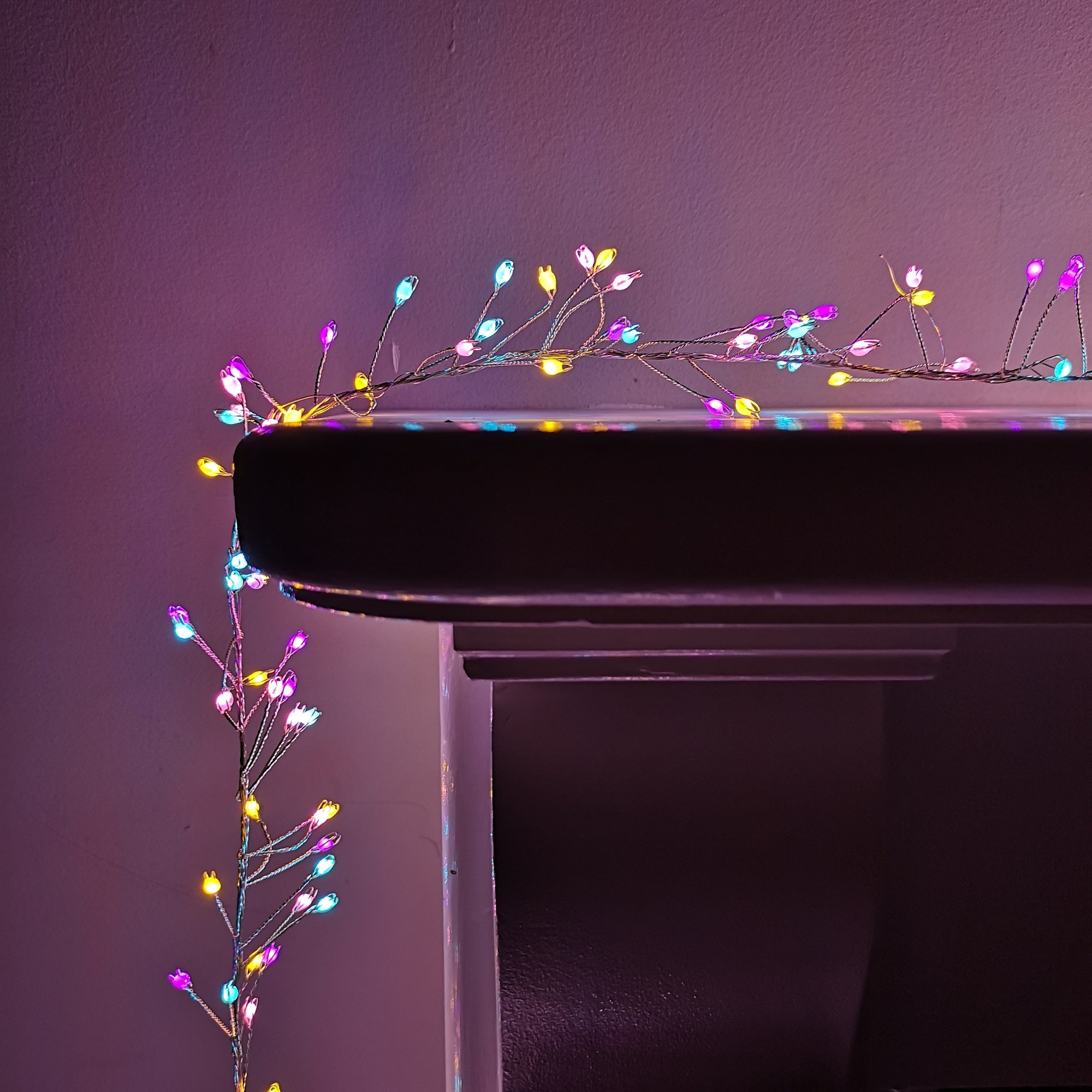 Colorful 800 LED cluster lights in rainbow hues, featuring delicate wire branches, draped elegantly over a dark surface, with a timer function for convenience.