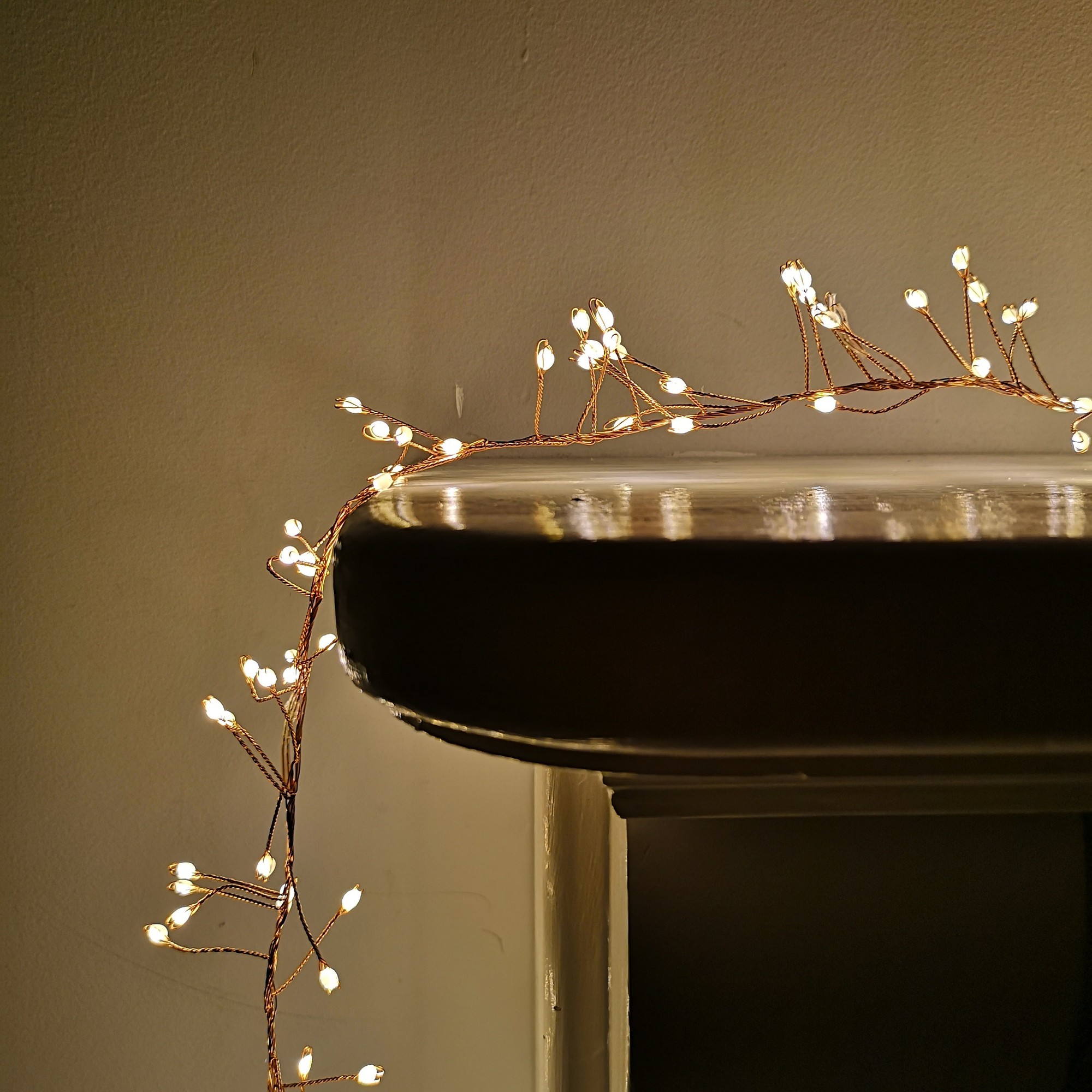 Warm white LED cluster lights on a flexible brown wire, featuring 800 bulbs, elegantly draped over a dark surface, ideal for festive decorations with a built-in timer.