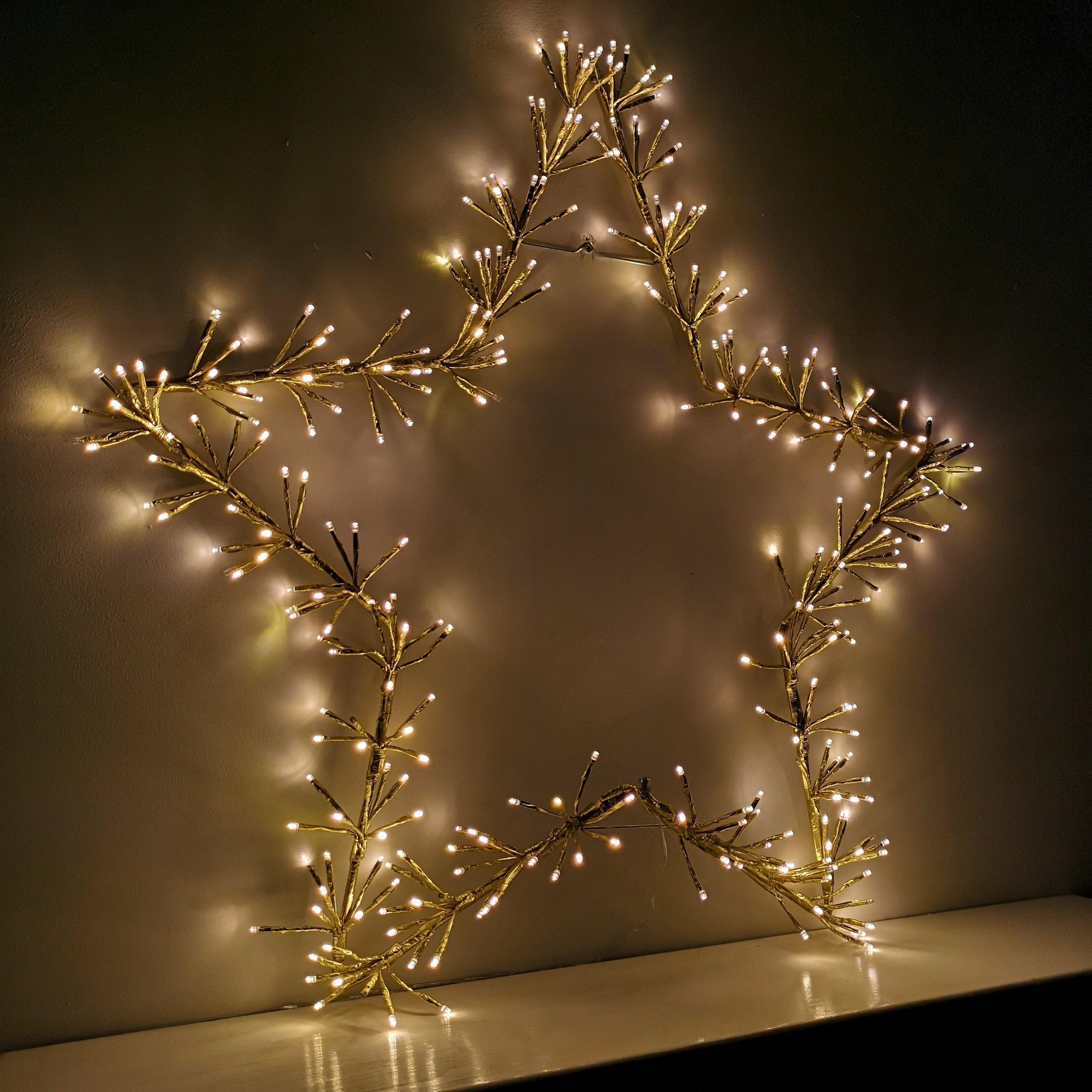 90cm gold star silhouette Christmas decoration featuring warm white twinkling LED lights, crafted from flexible branches for a festive glow.