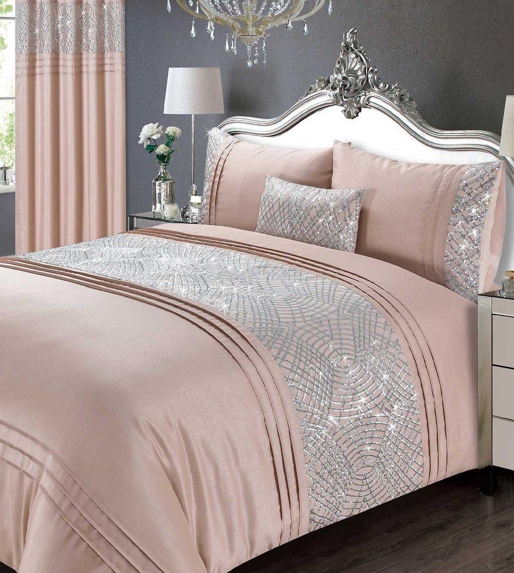 Blush pink duvet cover set featuring glitter sequins and elegant silver detailing, complemented by matching pillowcases and a decorative cushion on a stylish bed.