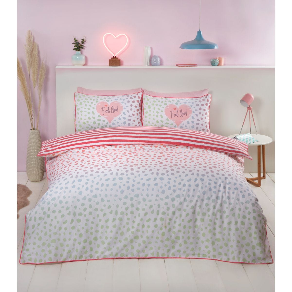Dalmation Blush double duvet cover set featuring a playful polka dot pattern in pastel colors, complemented by striped pillowcases and a pink trim, set against a soft, light backdrop.