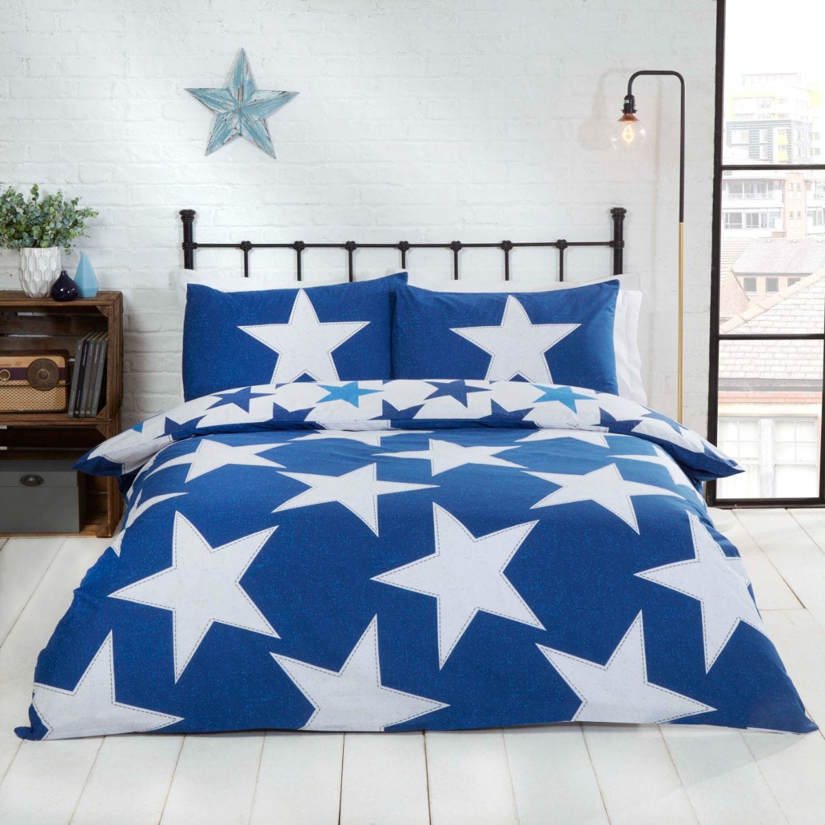 Navy and blue duvet set featuring large white stars, made from soft fabric, complemented by matching star-patterned pillowcases, styled in a cozy bedroom setting.