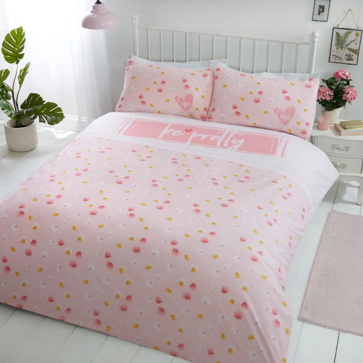 King-sized duvet set in soft pink with floral patterns and the phrase "be pretty" in white, complemented by matching pillowcases, perfect for a cheerful bedroom decor.