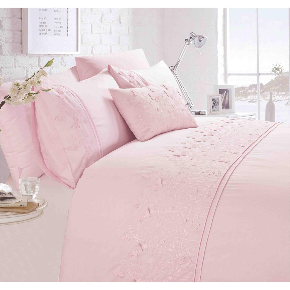 Blush pink duvet set featuring delicate butterfly embroidery, complemented by matching pillowcases and decorative cushions, set against a bright, airy bedroom backdrop.