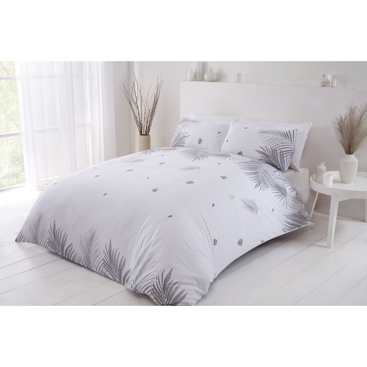 King-sized duvet set in grey featuring a tropical leaf pattern, made from soft fabric, complemented by matching pillowcases, set against a bright, airy bedroom backdrop.