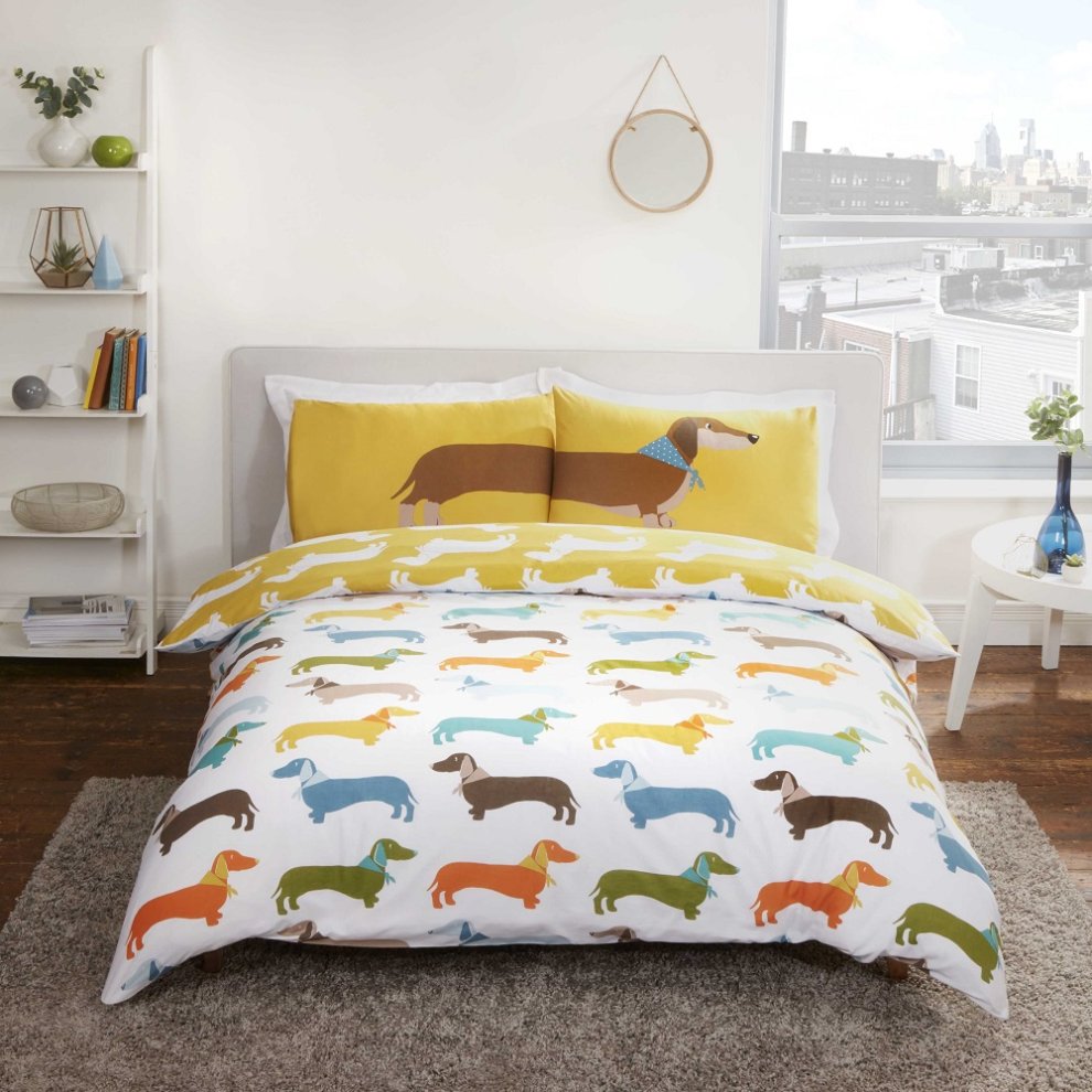 Multi-colored reversible duvet set featuring playful sausage dog designs in blue, orange, brown, and yellow, with a bright yellow pillowcase showcasing a dog wearing a blue scarf.