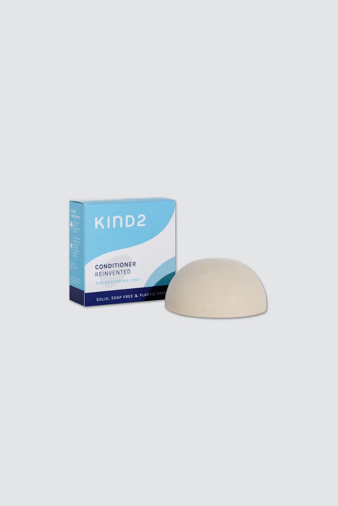 Creamy beige solid conditioner bar next to a blue and white box labeled "KIND2," highlighting its eco-friendly, plastic-free packaging.