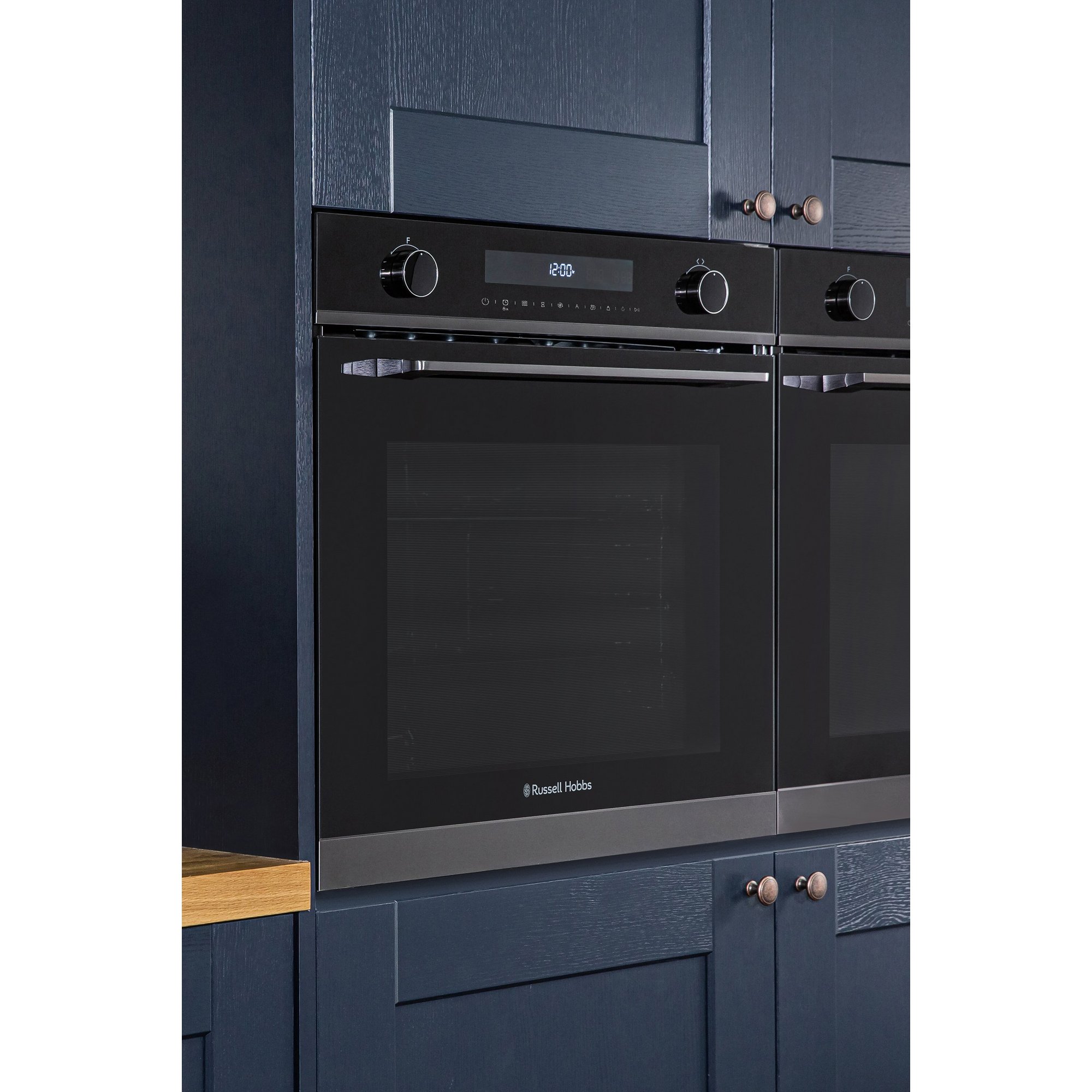 Black Russell Hobbs RHMEO7202DS electric single oven and microwave with a sleek glass front, control knobs, digital display, and integrated into navy blue cabinetry.