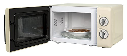 Compact cream-colored microwave with a black door, featuring a white interior, a circular plate inside, and two dials for time and power settings.