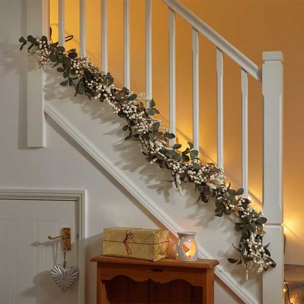 1.8m white winter berry Christmas garland featuring seasonal foliage, adorned with white berries and greenery, elegantly draped along a staircase railing.