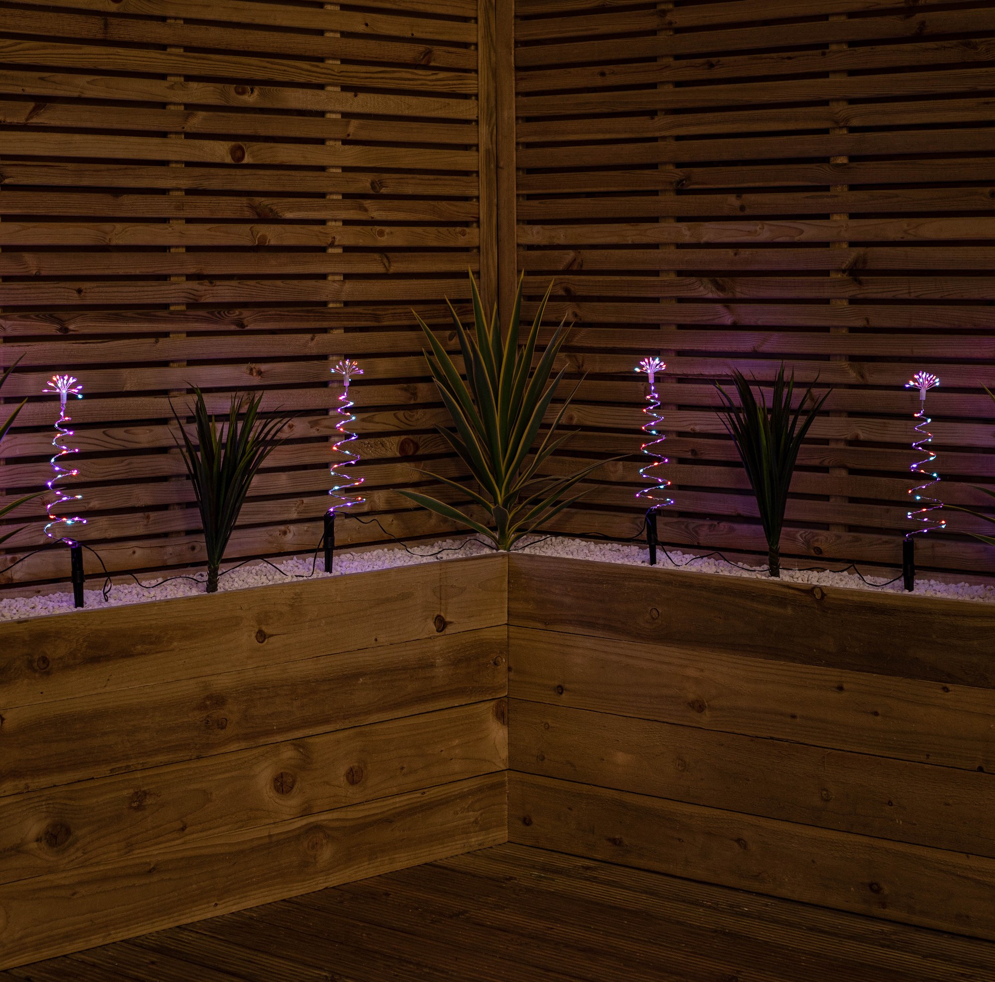 Set of 4 light-up silver Christmas tree path lights, 30cm tall, featuring 200 rainbow LEDs, displayed against a wooden backdrop with decorative plants.