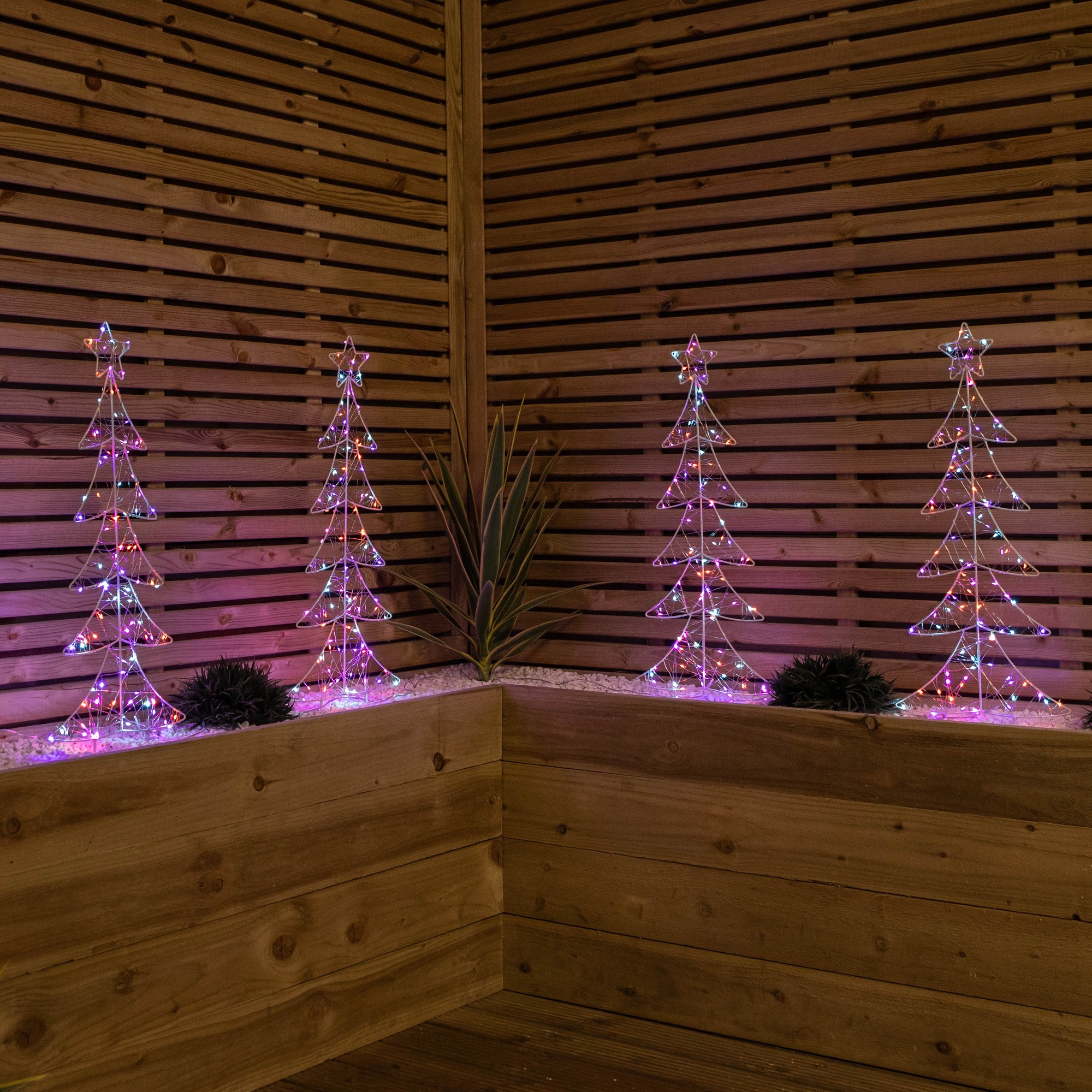 Set of 4 light-up Christmas tree path lights, 80cm tall, featuring 400 rainbow LEDs, with a transparent design and a wooden backdrop, enhancing festive decor.