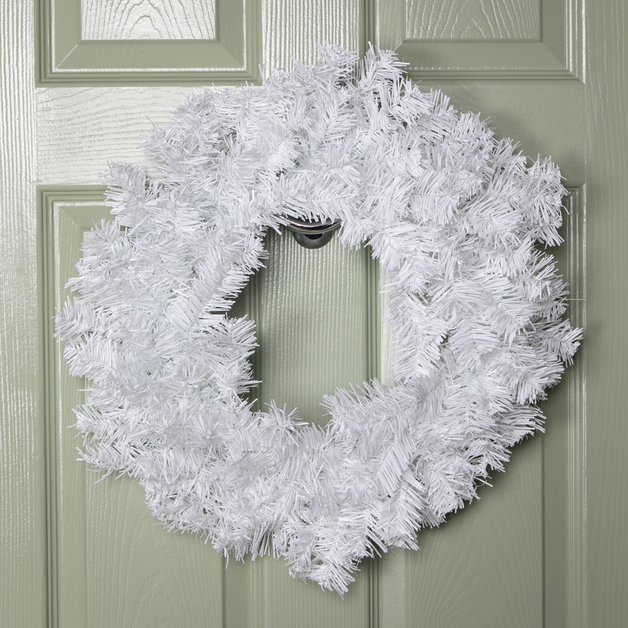 A 50cm plain white Christmas wreath made of PVC branches, featuring a fluffy texture, hanging on a green door.