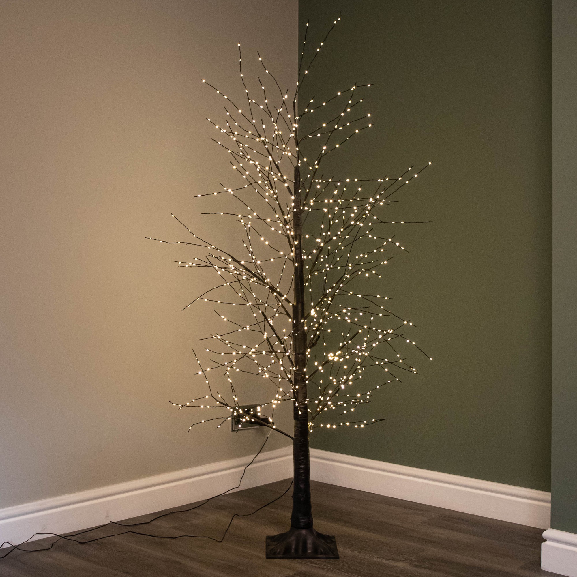 5ft black micro dot Christmas tree with a sturdy base, adorned with 900 warm white LEDs, featuring both static and twinkling light options, set against a green wall.