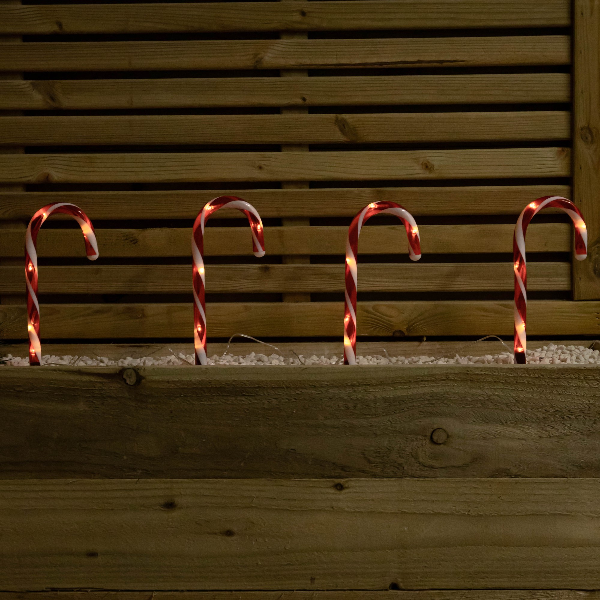 Set of 12 battery-powered candy cane path lights, each 25cm tall, featuring red and white striped designs with warm white LEDs illuminating the candy canes.