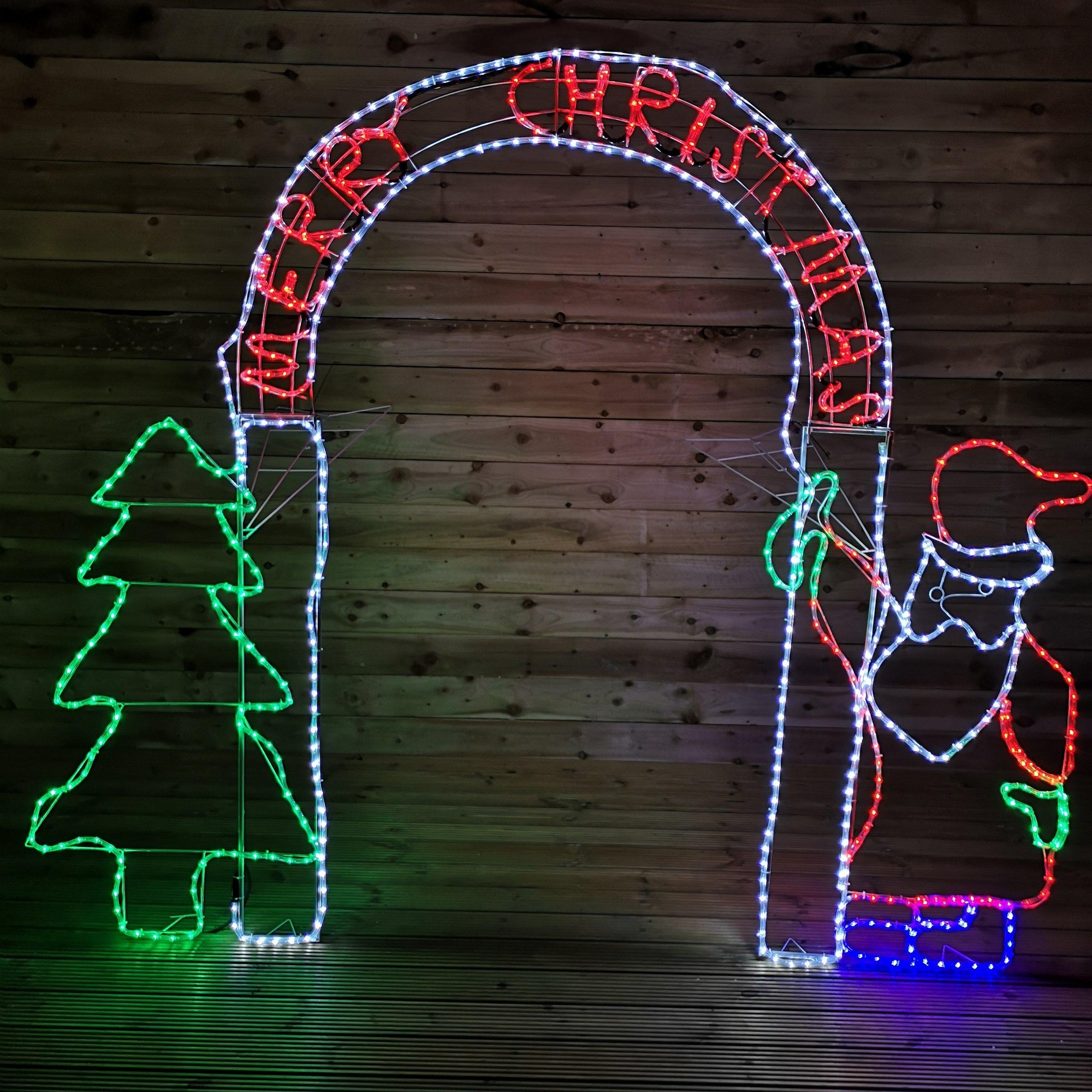 An 8ft LED Christmas archway featuring a colorful Santa with a red hat and a green tree, illuminated with bright white and colored lights, spelling "MERRY CHRISTMAS" at the top.