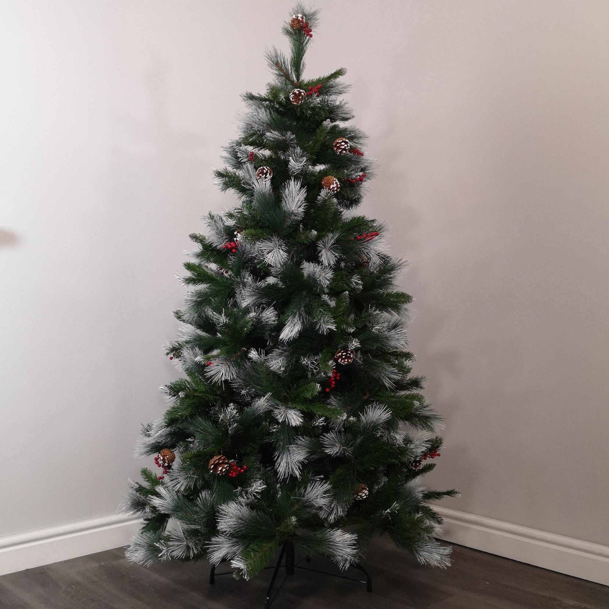 7ft green Avatika Christmas tree with frosted tips, adorned with cones and red berries, featuring 896 tips and a sturdy black base.