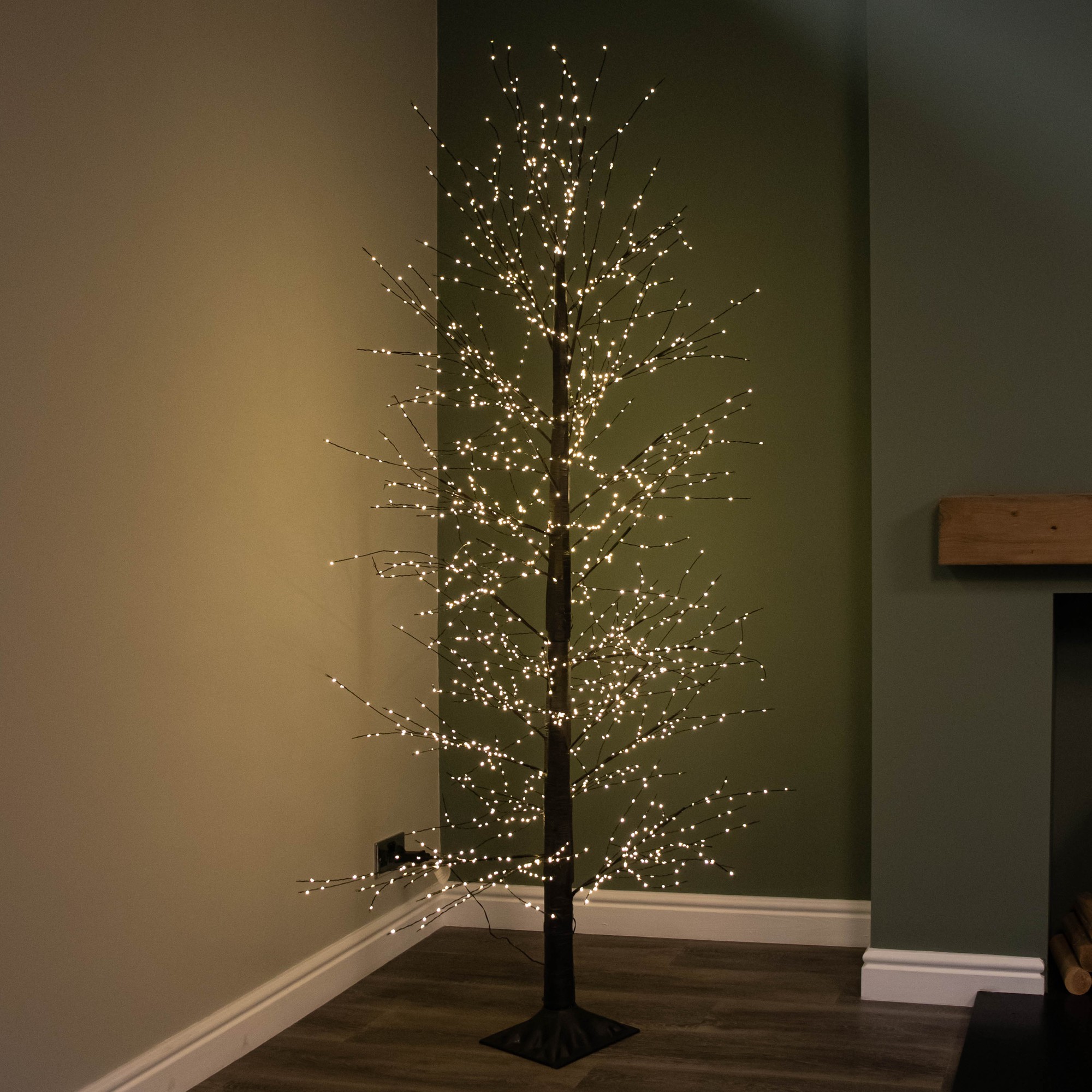 7ft black micro dot Christmas tree featuring 1700 warm white LEDs, with a slim design and twinkling effects, set against a muted green wall.
