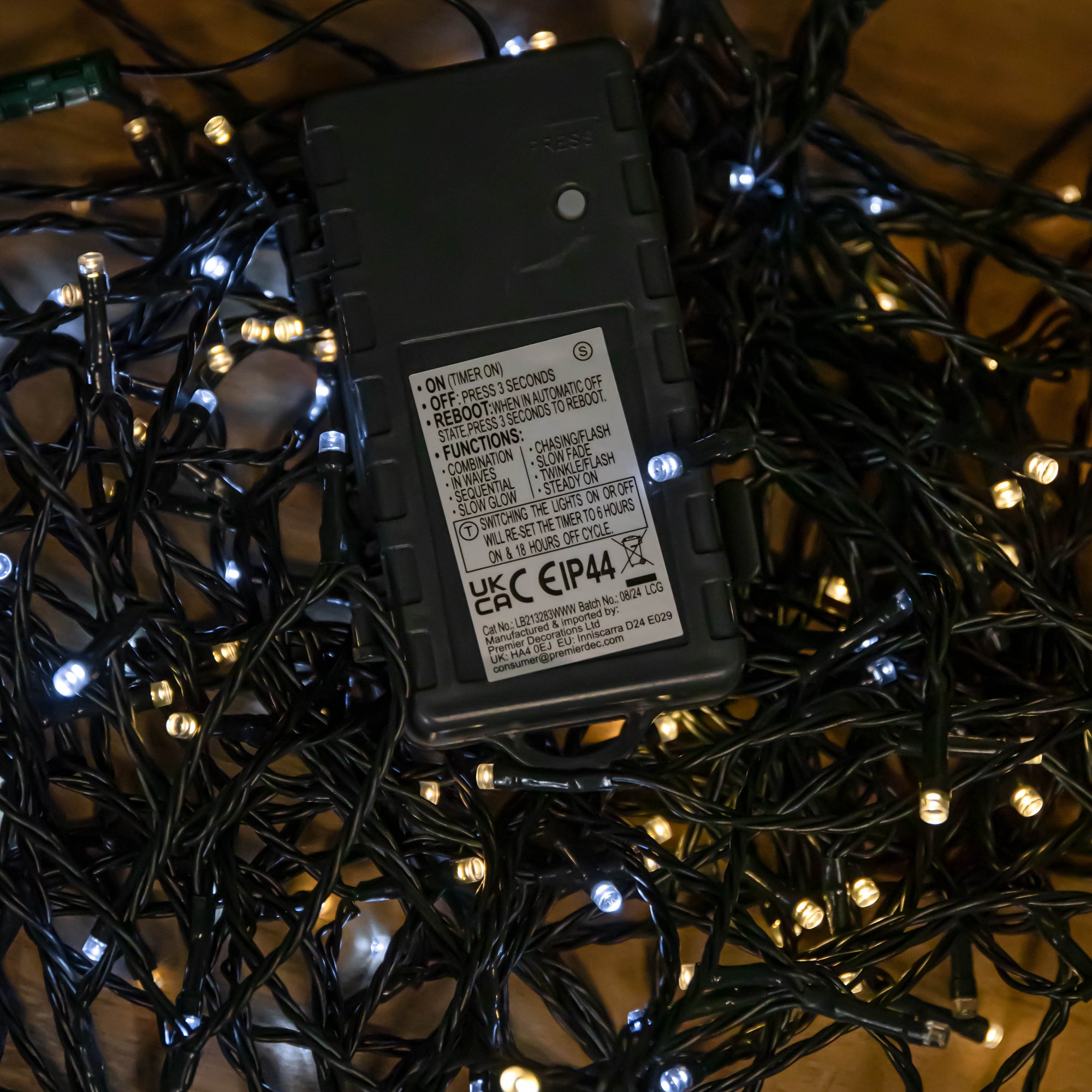 Battery-operated Christmas string lights featuring 1000 LEDs in cool and warm white, set against a backdrop of dark green wire, with a black battery pack visible.