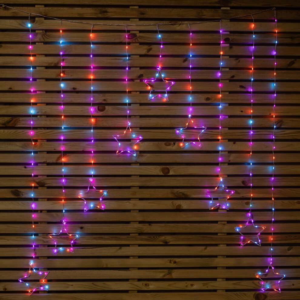Colorful curtain lights featuring 258 rainbow LEDs in star shapes, hanging vertically against a wooden slatted background, creating a festive atmosphere.