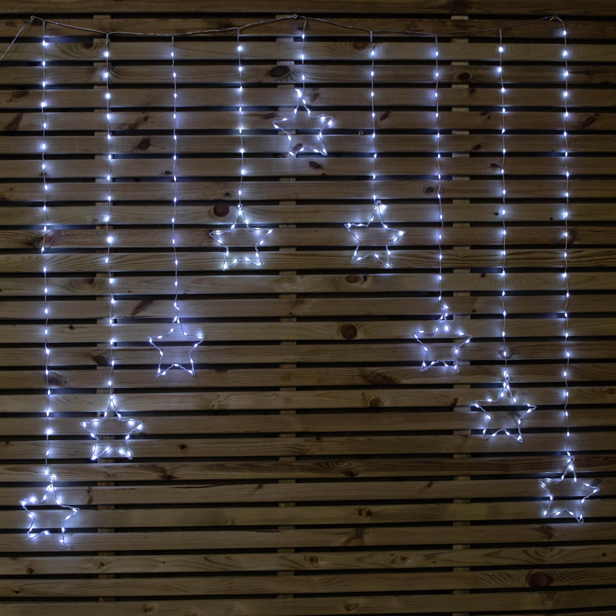 FlexiBrights Christmas star curtain lights feature 258 white LEDs in star shapes, hanging from a string against a wooden backdrop, creating a festive ambiance.