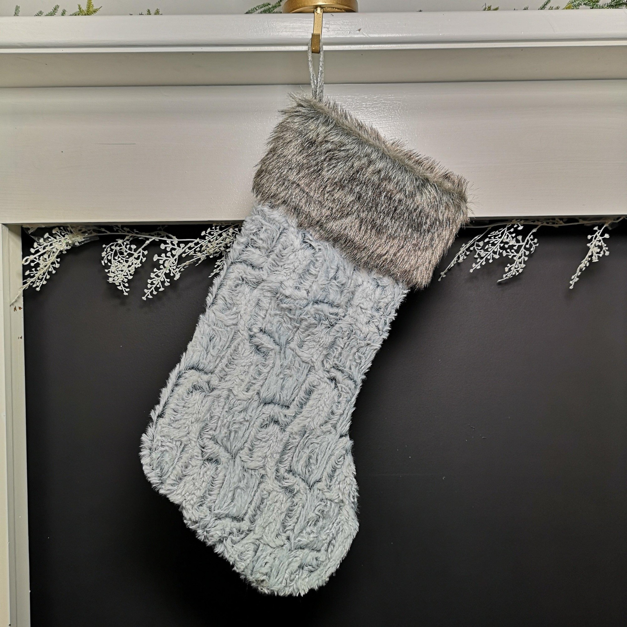 Grey festive Christmas stocking with a textured pattern, featuring a soft fur trim at the top, measuring 48cm, hanging from a hook.