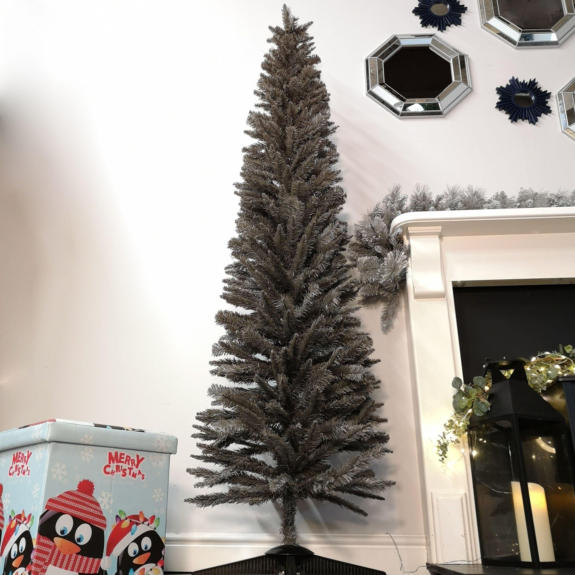 7ft grey pencil pine artificial Christmas tree with 401 tips, featuring a slim design and realistic foliage, placed next to a fireplace and decorative items.