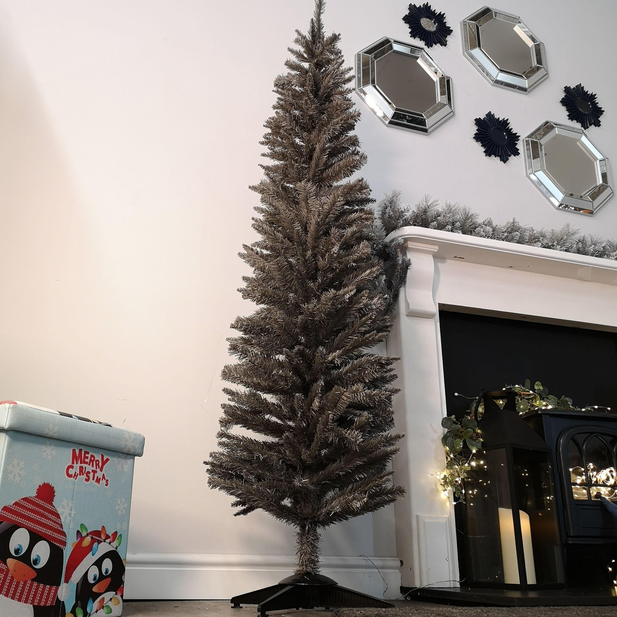 Slim 6ft grey artificial pencil pine Christmas tree with 321 tips, featuring a sturdy black base, set against a minimalist backdrop with decorative mirrors and a festive gift box.