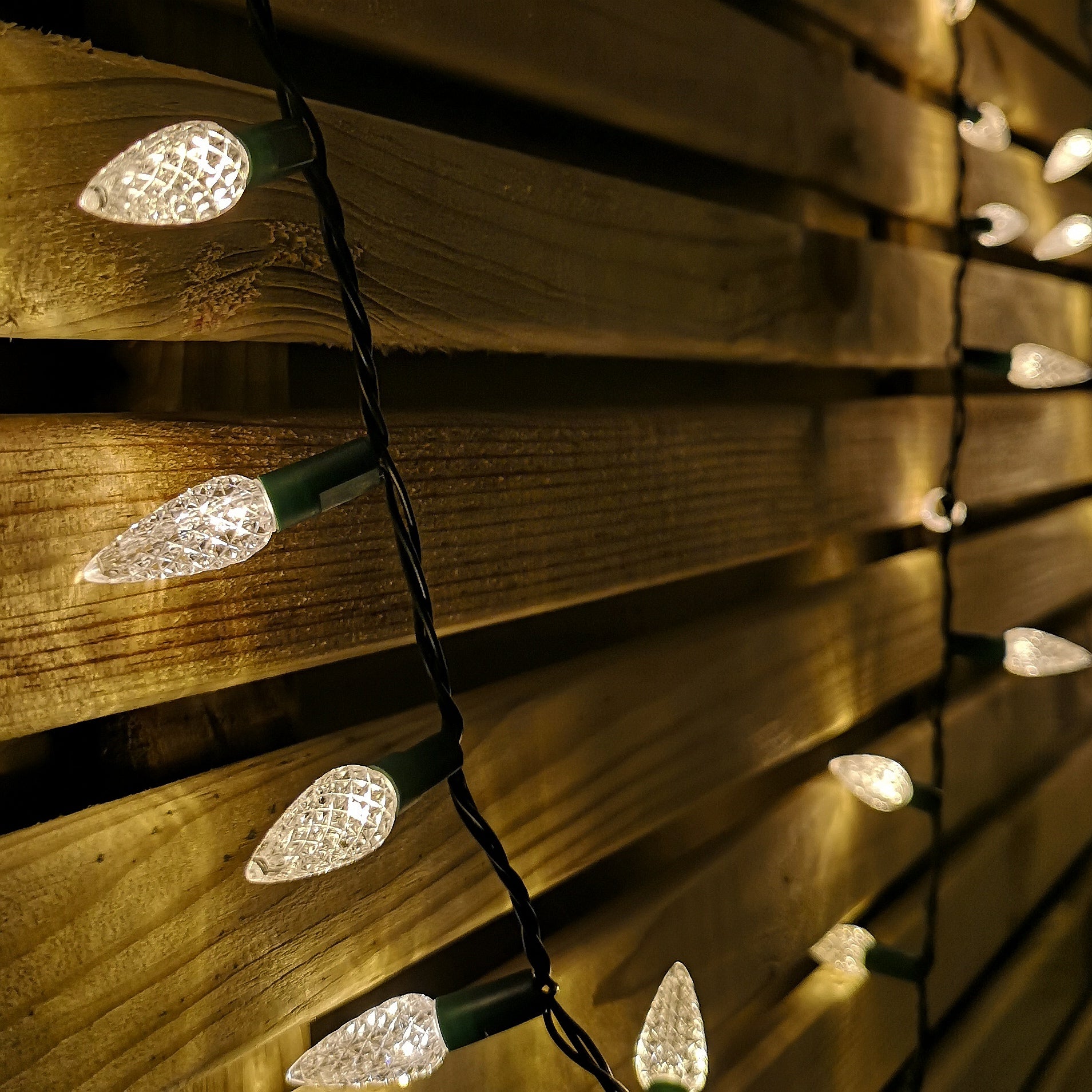 15m string of 300 warm white LED pine cone-shaped Christmas lights with a black wire, showcasing a cozy glow against a wooden background.