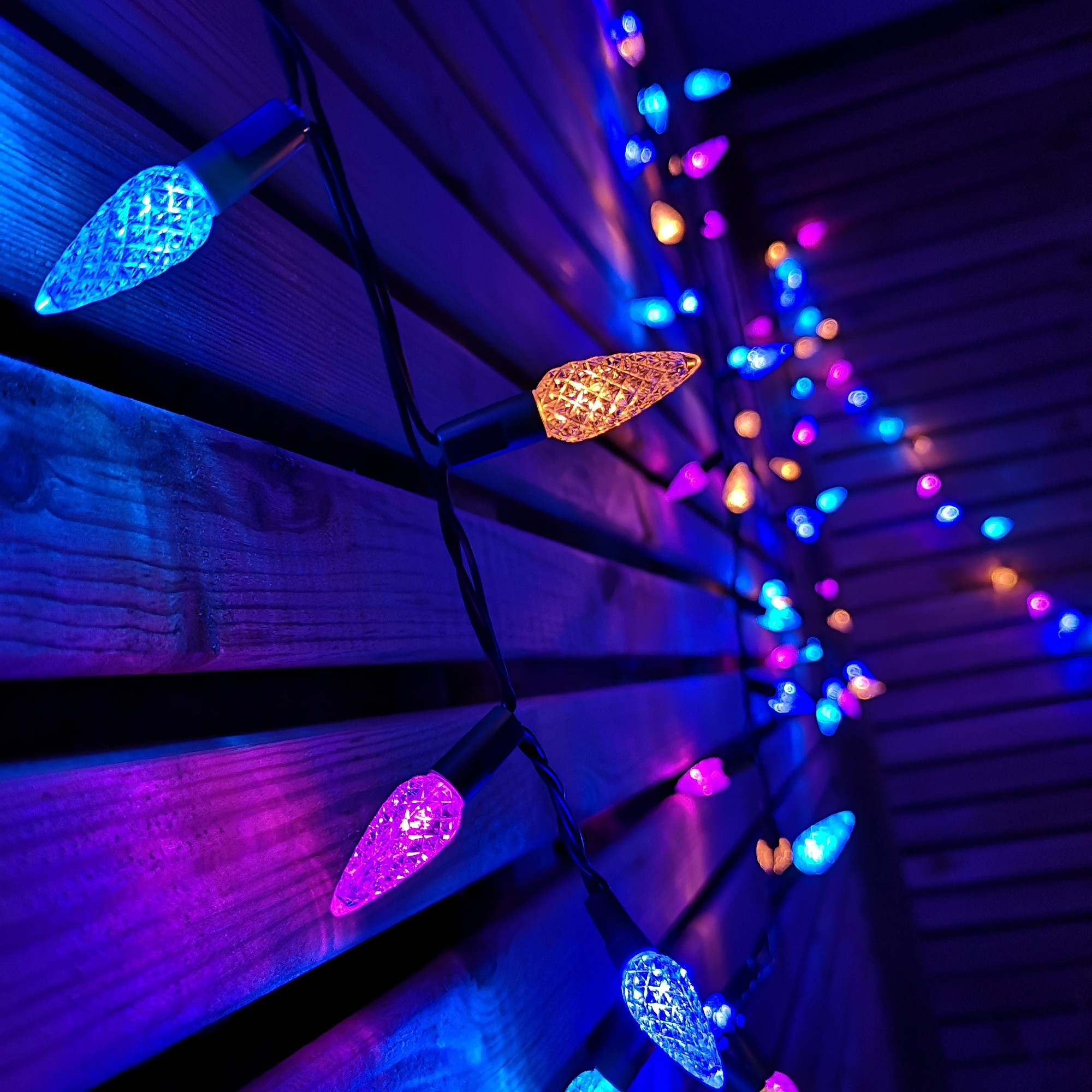 15m string of 300 LED Christmas lights featuring multi-colored pine cone-shaped bulbs in blue, purple, and orange, set against a wooden backdrop.