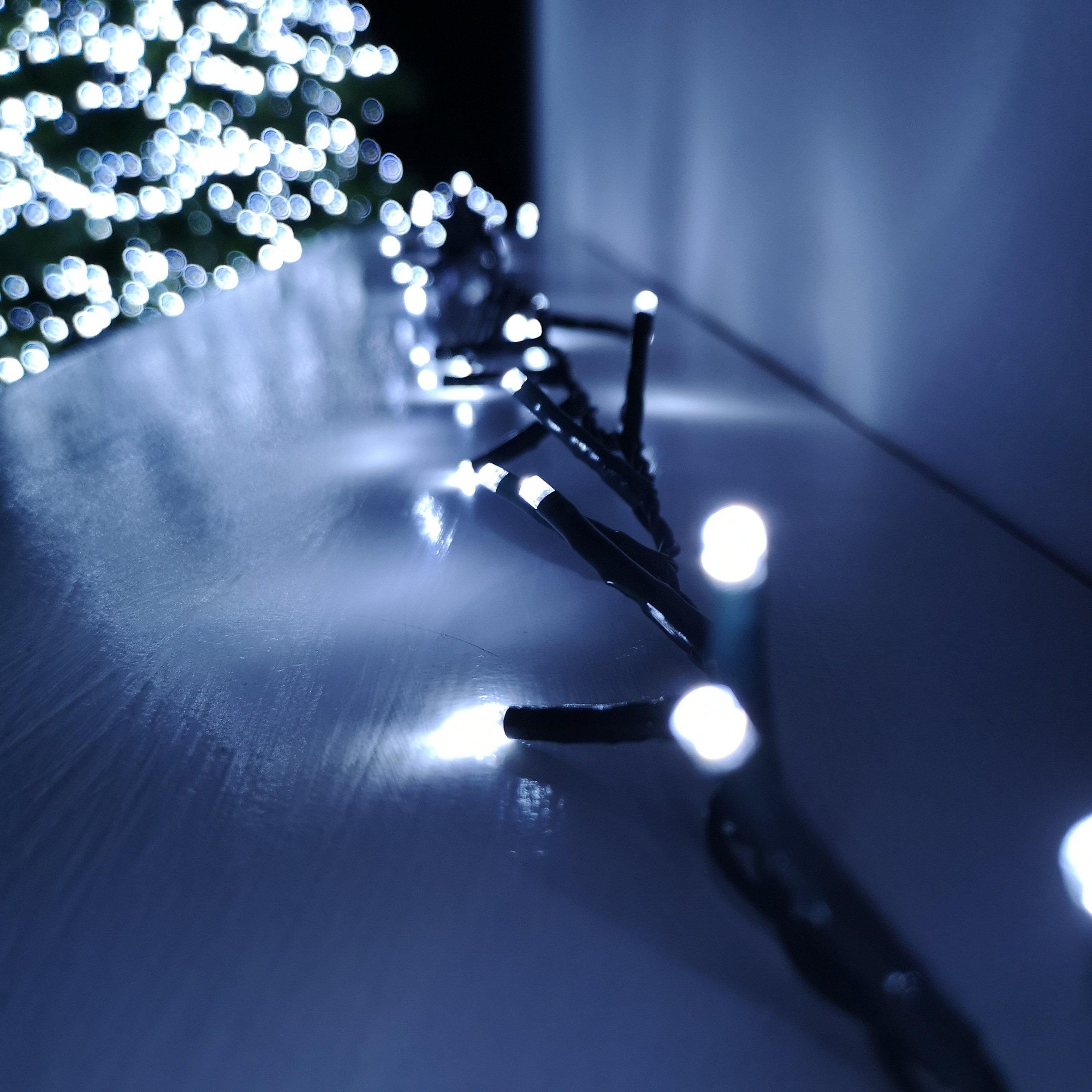 3000 LED string lights in cool white, featuring a mains-operated design with a timer, set against a blurred background of shimmering white lights.