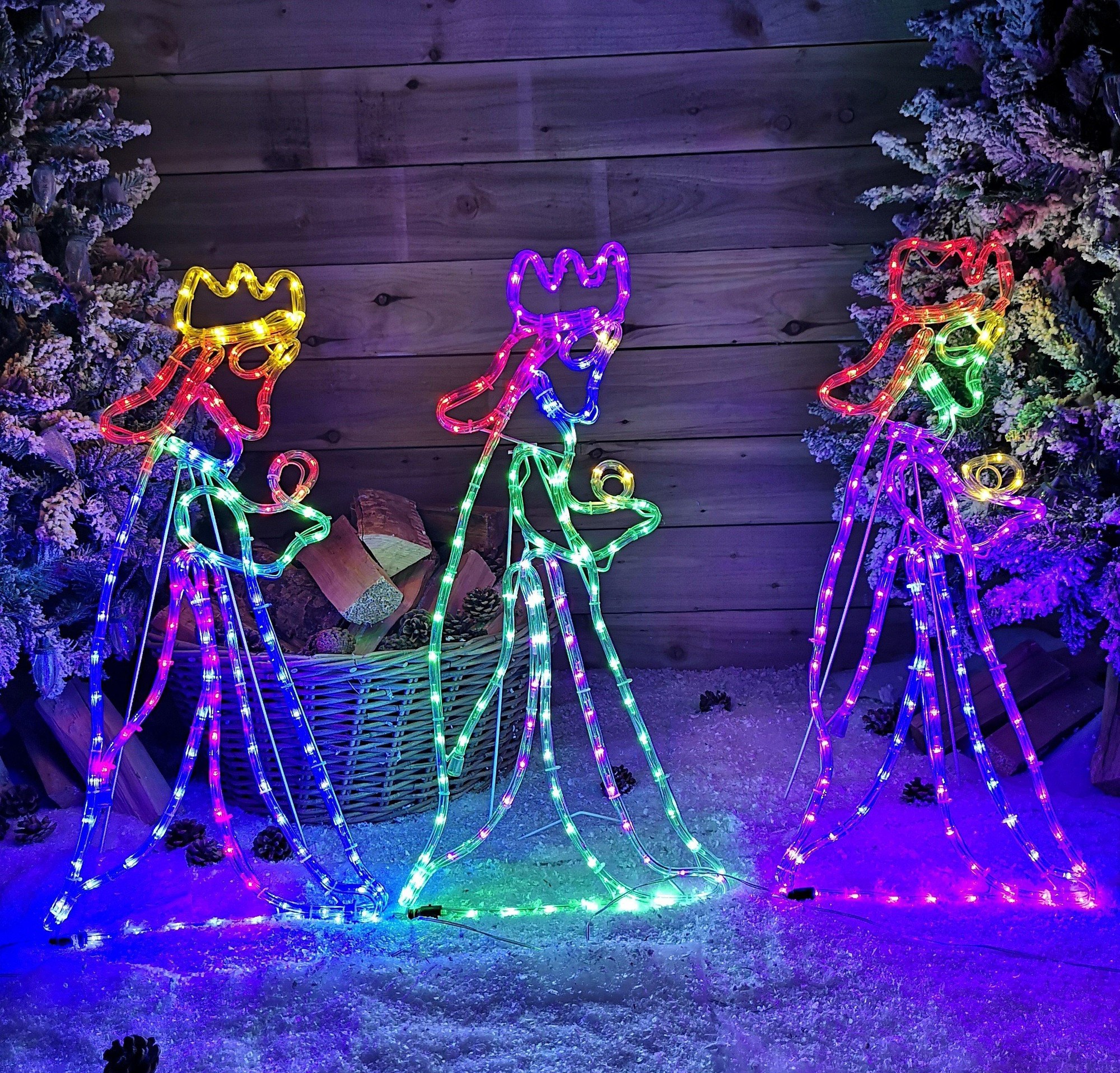Three illuminated silhouettes of the Wise Men, each adorned with colorful LED lights in vibrant hues, set against a snowy backdrop, showcasing festive holiday spirit.
