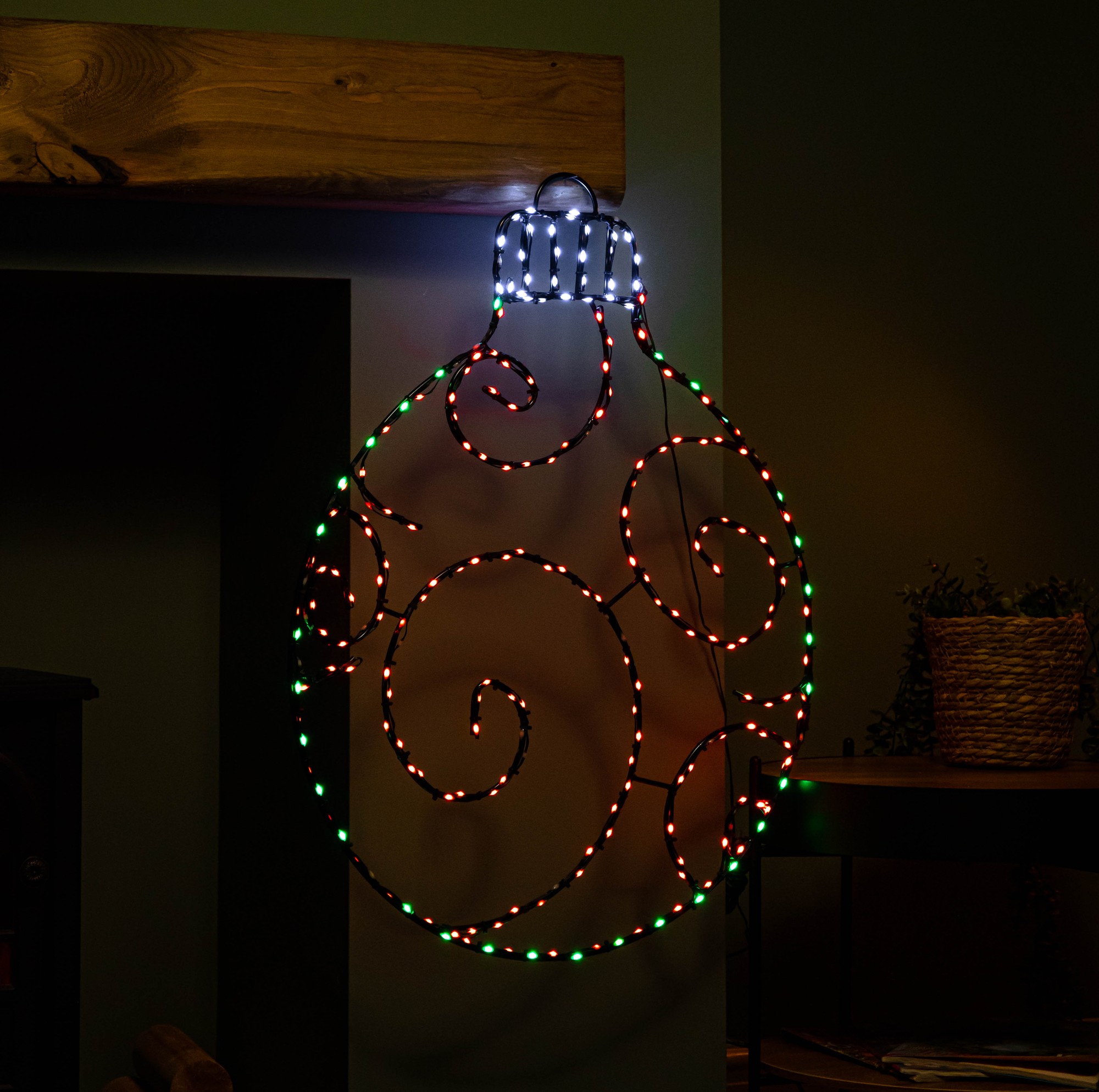 Large 78cm metal hanging Christmas bauble in red and green, featuring 245 static and twinkling LEDs, with elegant swirling designs and a black top, displayed against a dark wall.