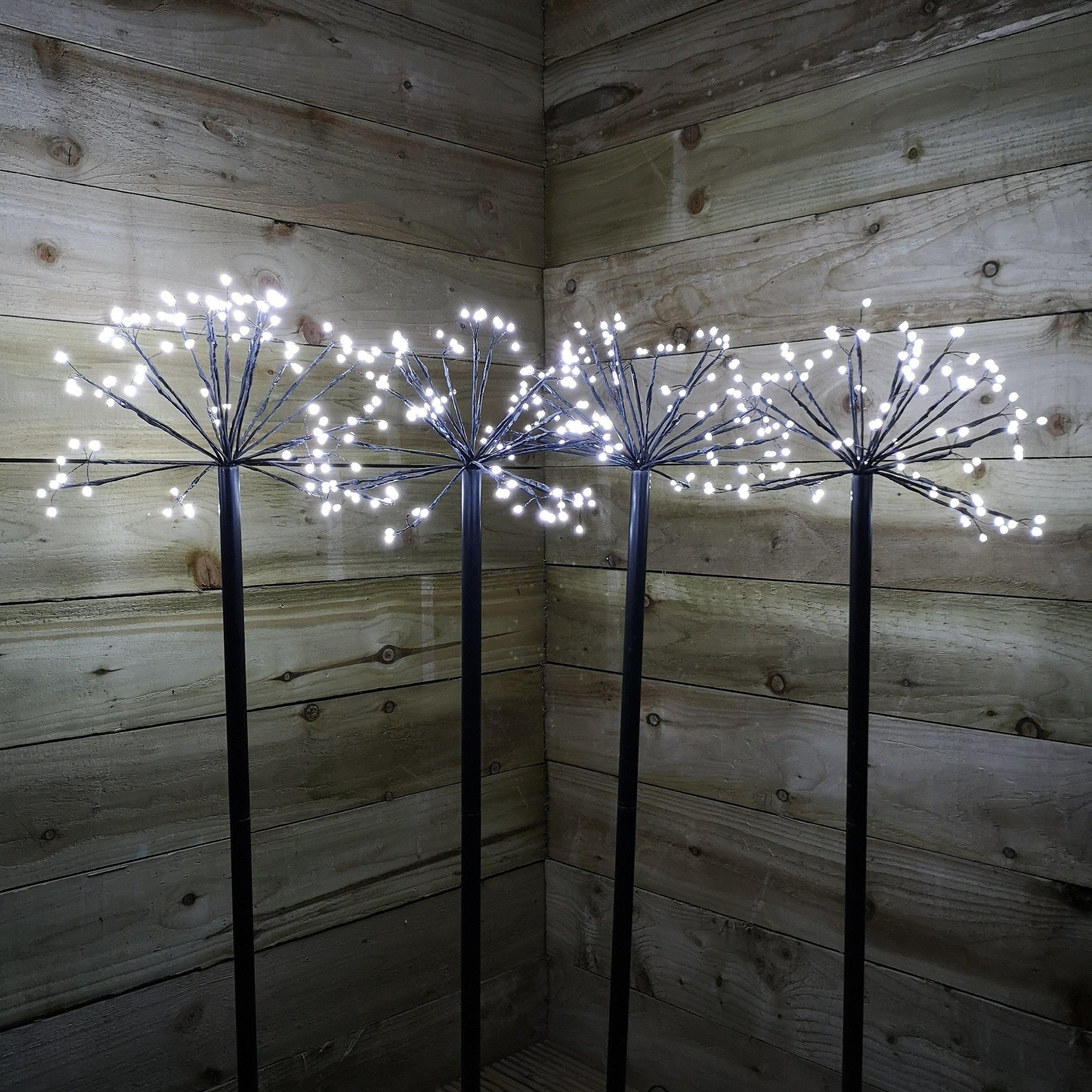 Four 100cm tall black metal path lights with cool white LED sparkler designs, featuring 400 bright white lights, set against a rustic wooden background.