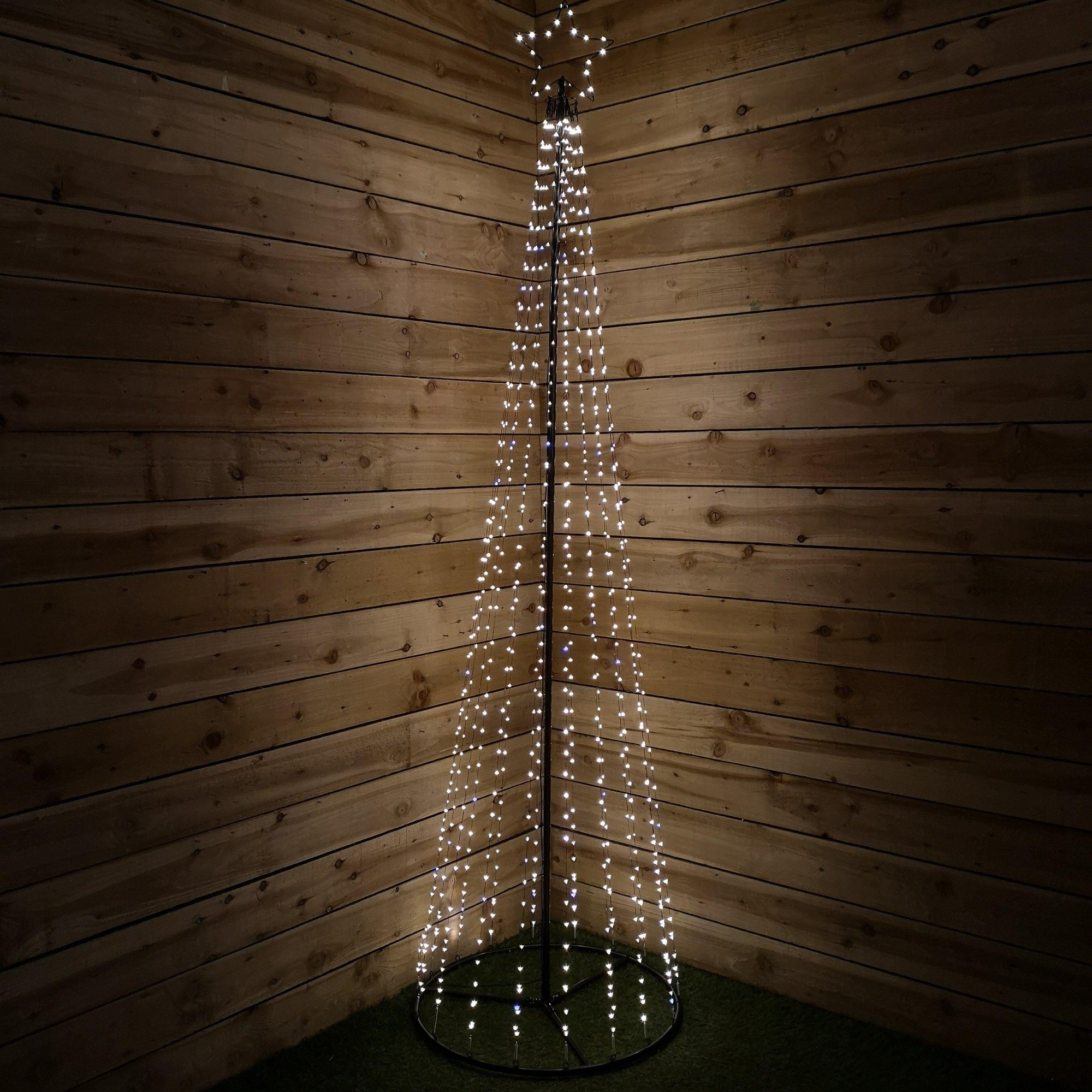 A 2.5-meter maypole tree structure made of black metal, adorned with white flashing wire lights, set against a wooden wall background.