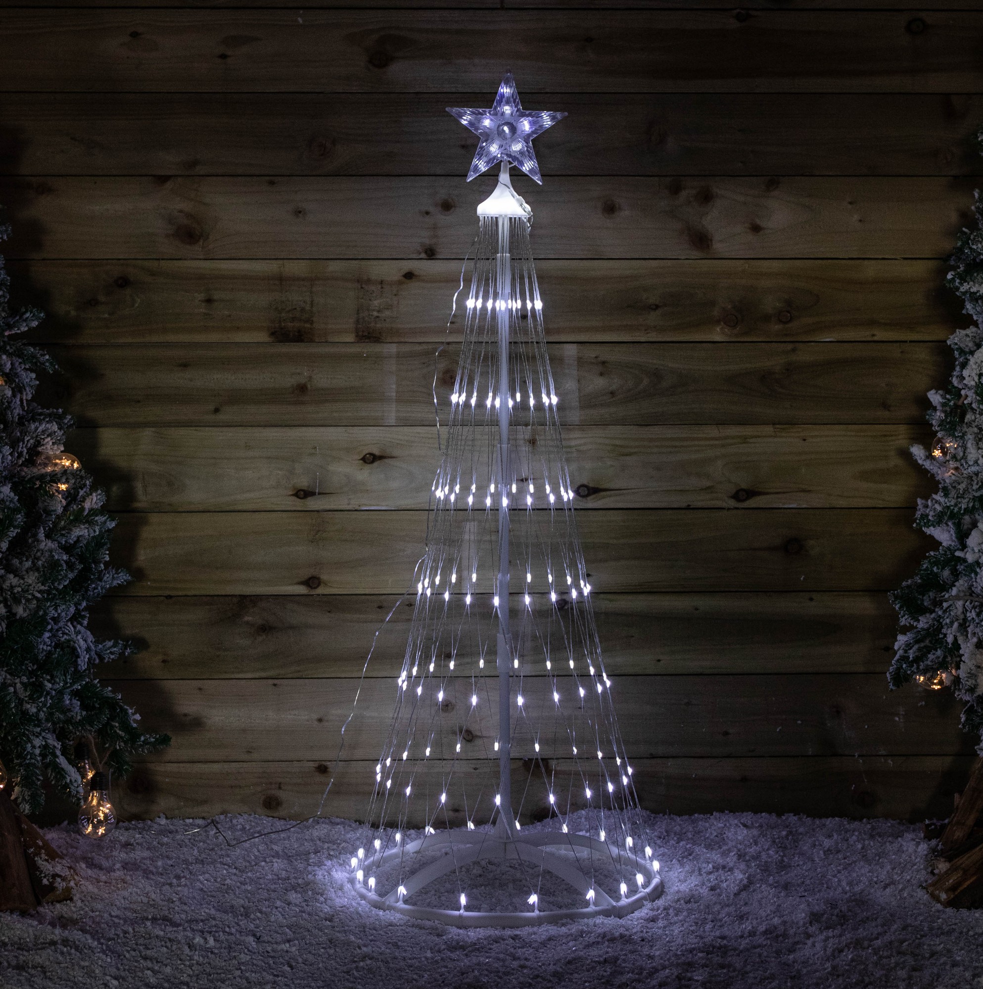 1.35M white Christmas cone tree featuring 160 white LEDs, a star topper, and a timer function, set against a wooden backdrop with snowy decorations.