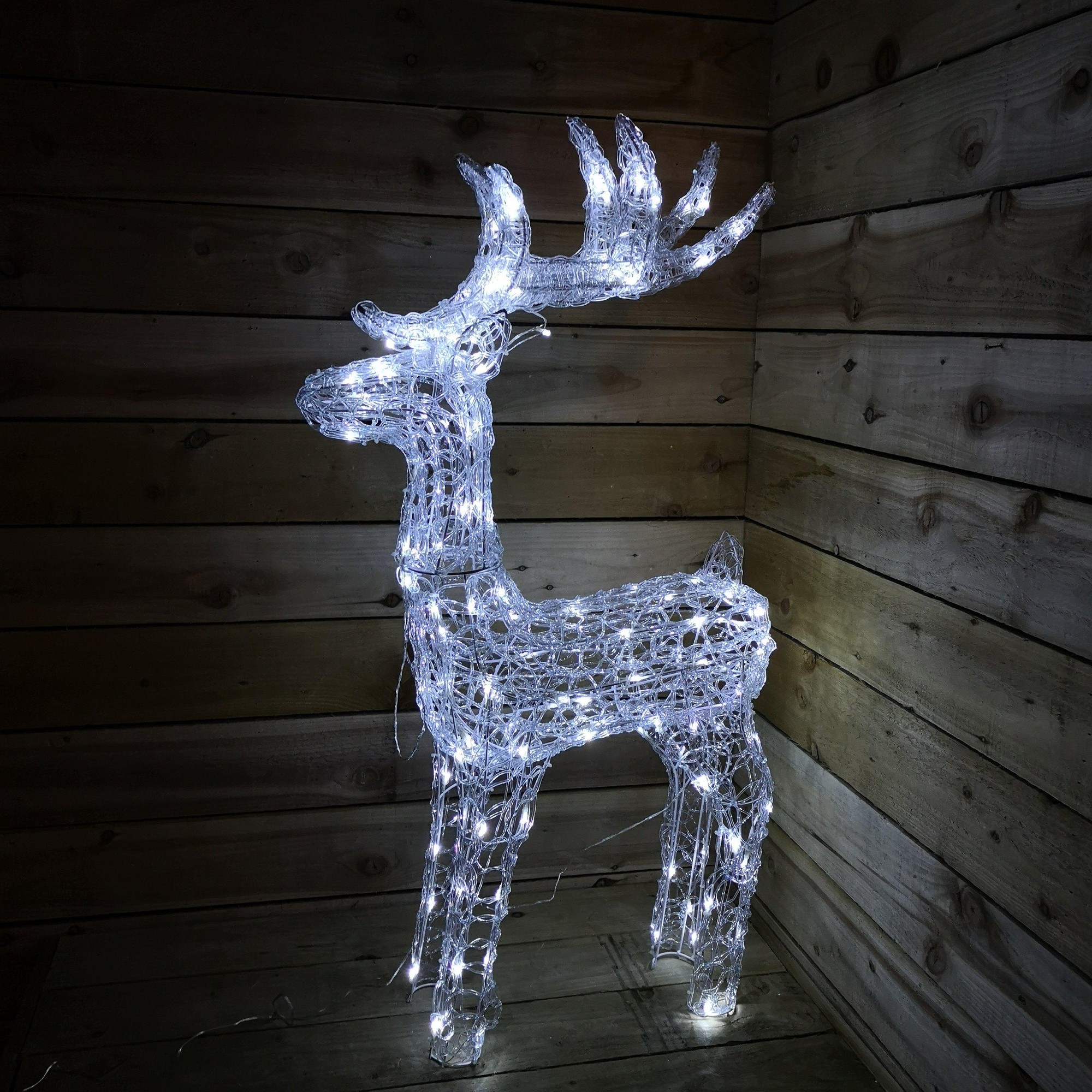 Soft acrylic reindeer sculpture with 160 white LED lights, featuring a detailed design and antlers, illuminated against a wooden backdrop.
