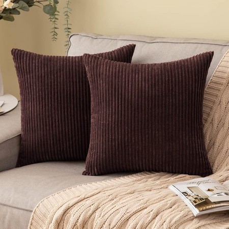 Set of 2 dark brown corduroy cushions, each measuring 45x45 cm, featuring a ribbed texture, placed on a light-colored sofa with a knitted throw and a magazine nearby.